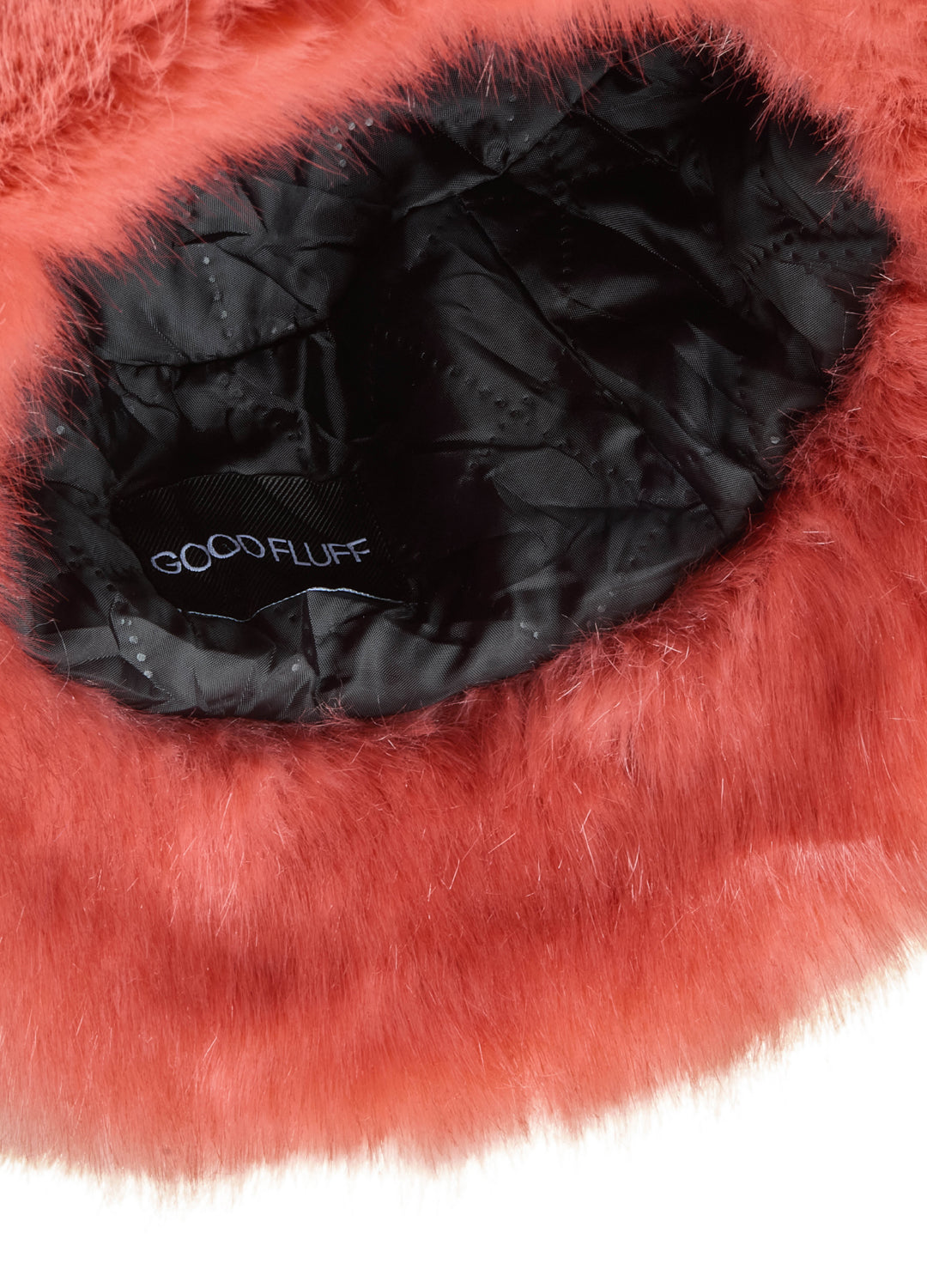 Close-up of a peachy red fur product with black interior and 'Good Fluff' branding.