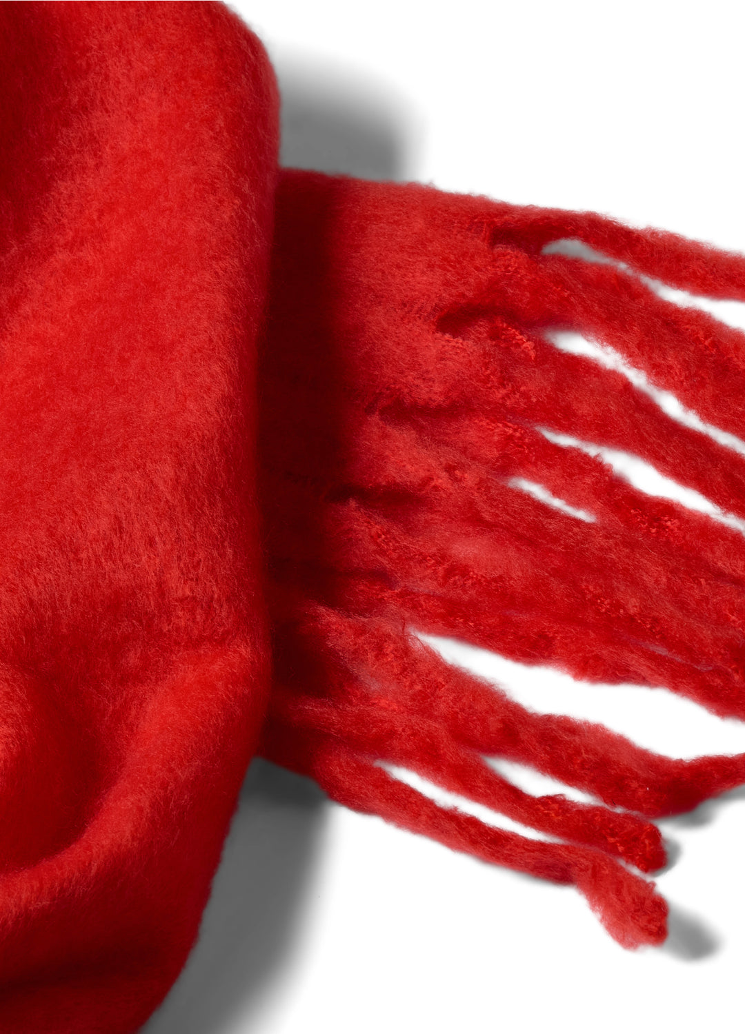 Close-up of a bright postbox red scarf with tassels on a white background