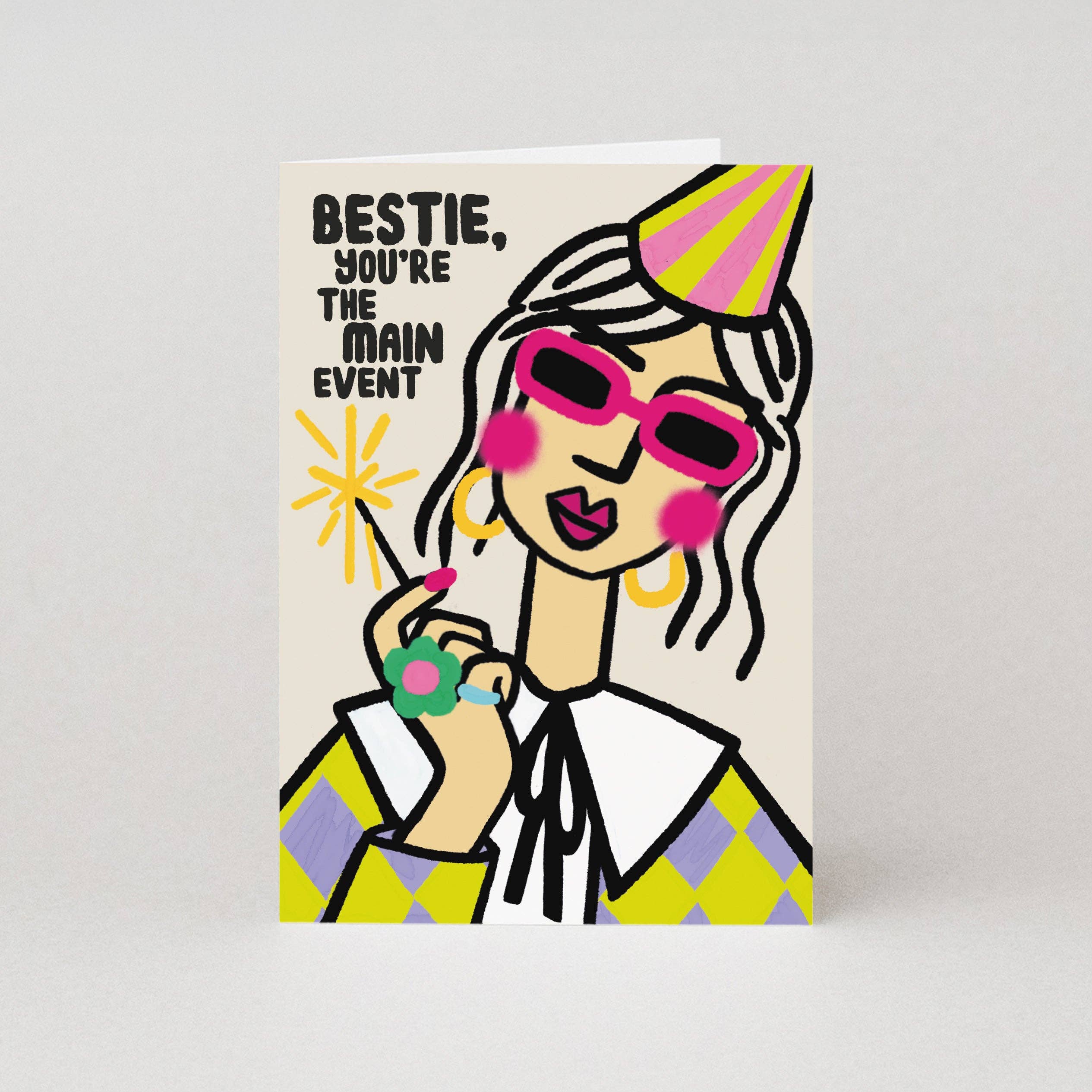 Greeting card with a stylized illustration of a woman wearing sunglasses and a party hat, with text 'Bestie, you're the main event' on a beige background.