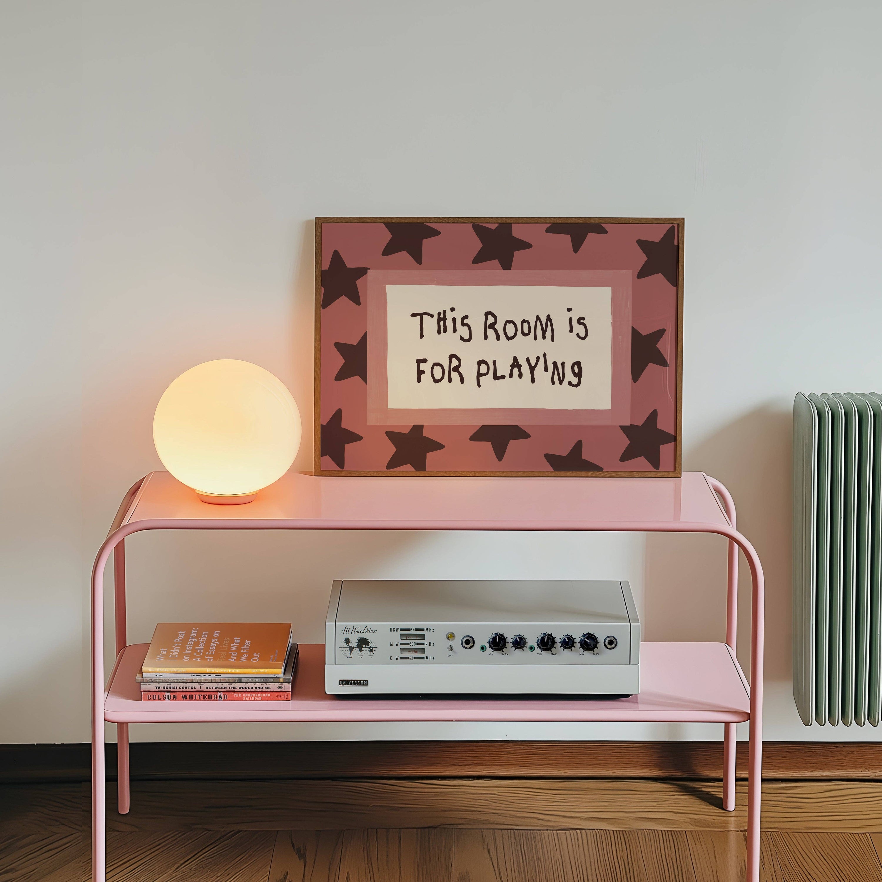 Pink shelf with a lamp, record player, and framed picture on a white wall.