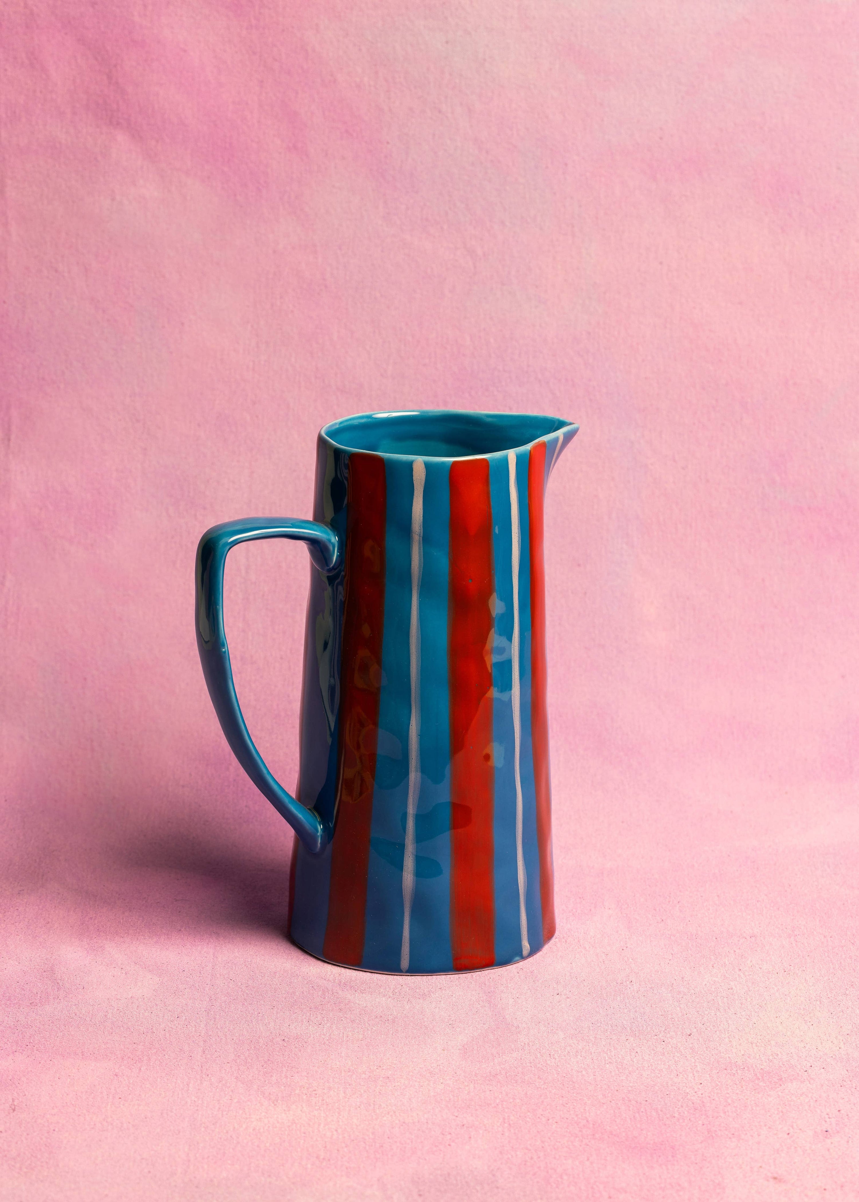 Colorful striped pitcher on a pink background