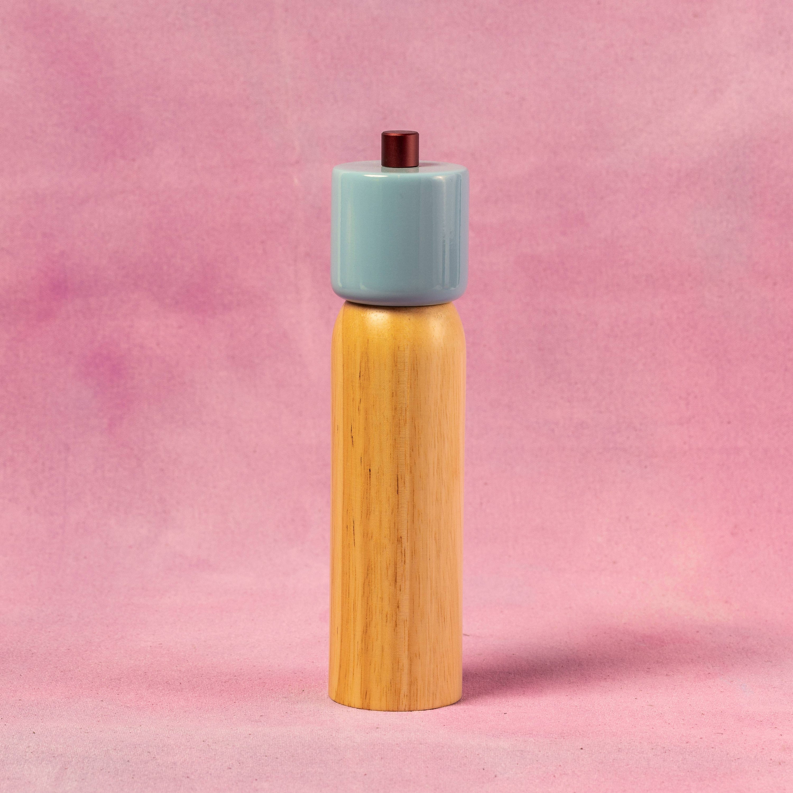 salt and pepper ginger with a light blue top and wooden body on a pink background
