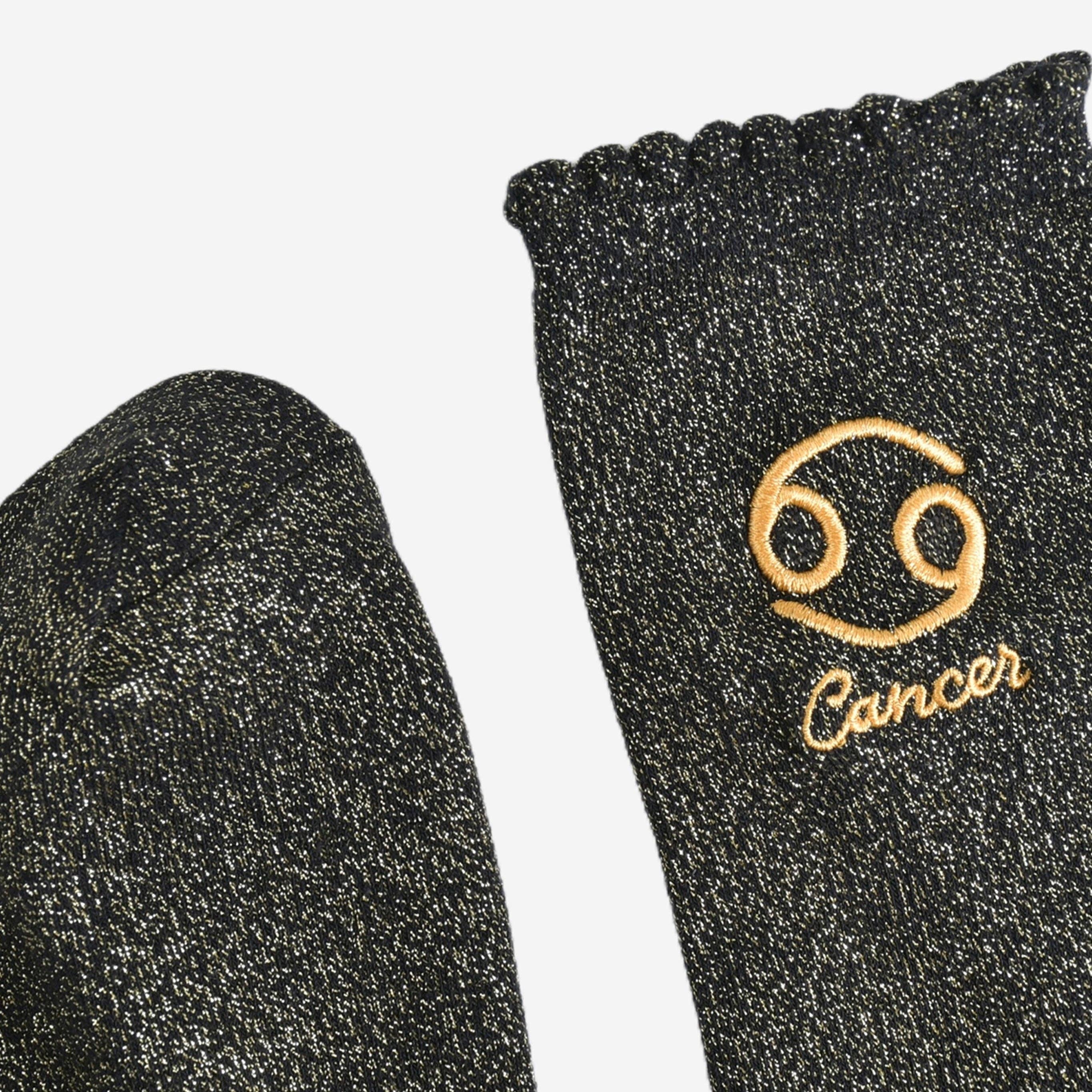 Black socks with gold embroidered Cancer symbol and text on a white background