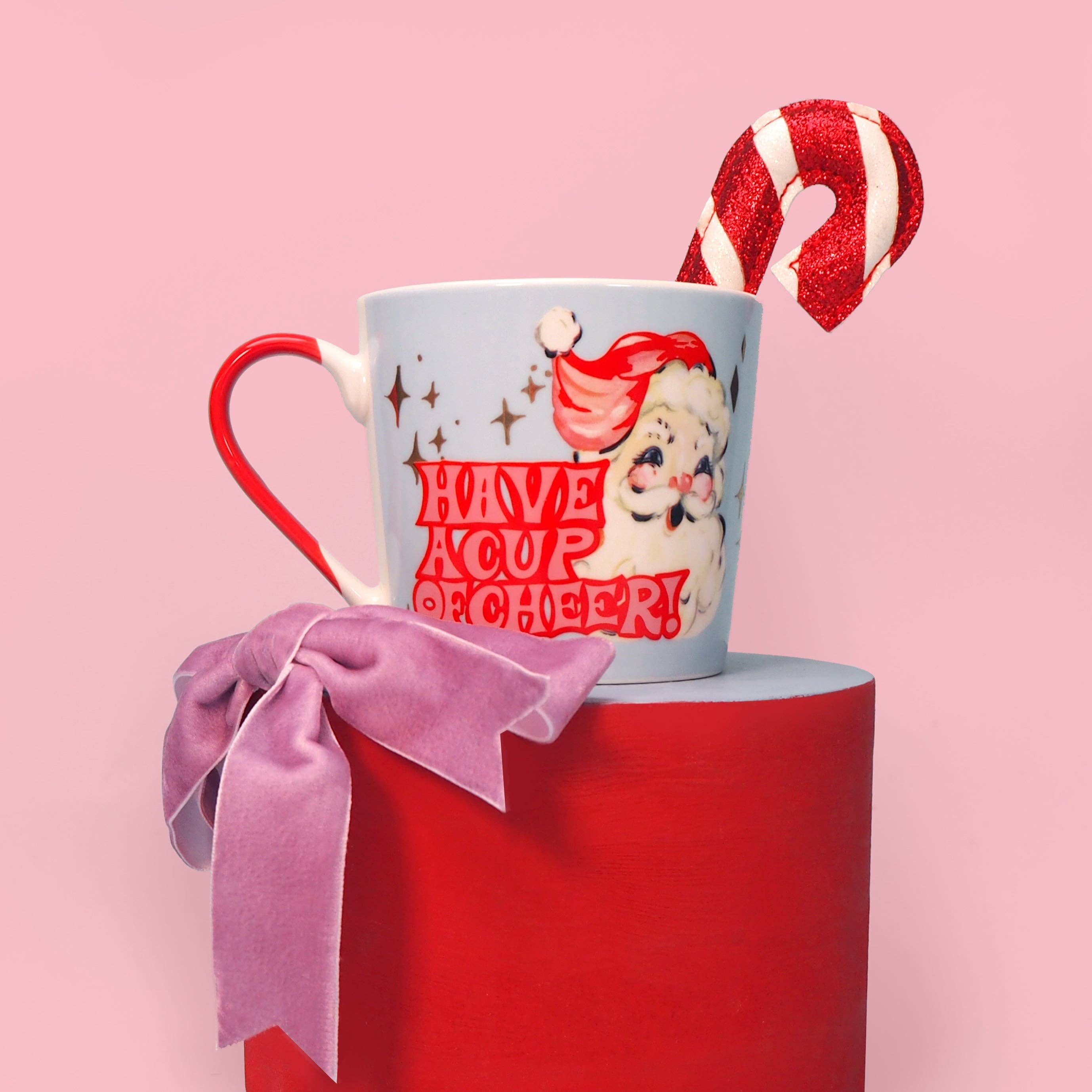 Christmas-themed mug with candy cane and bow on a pink background