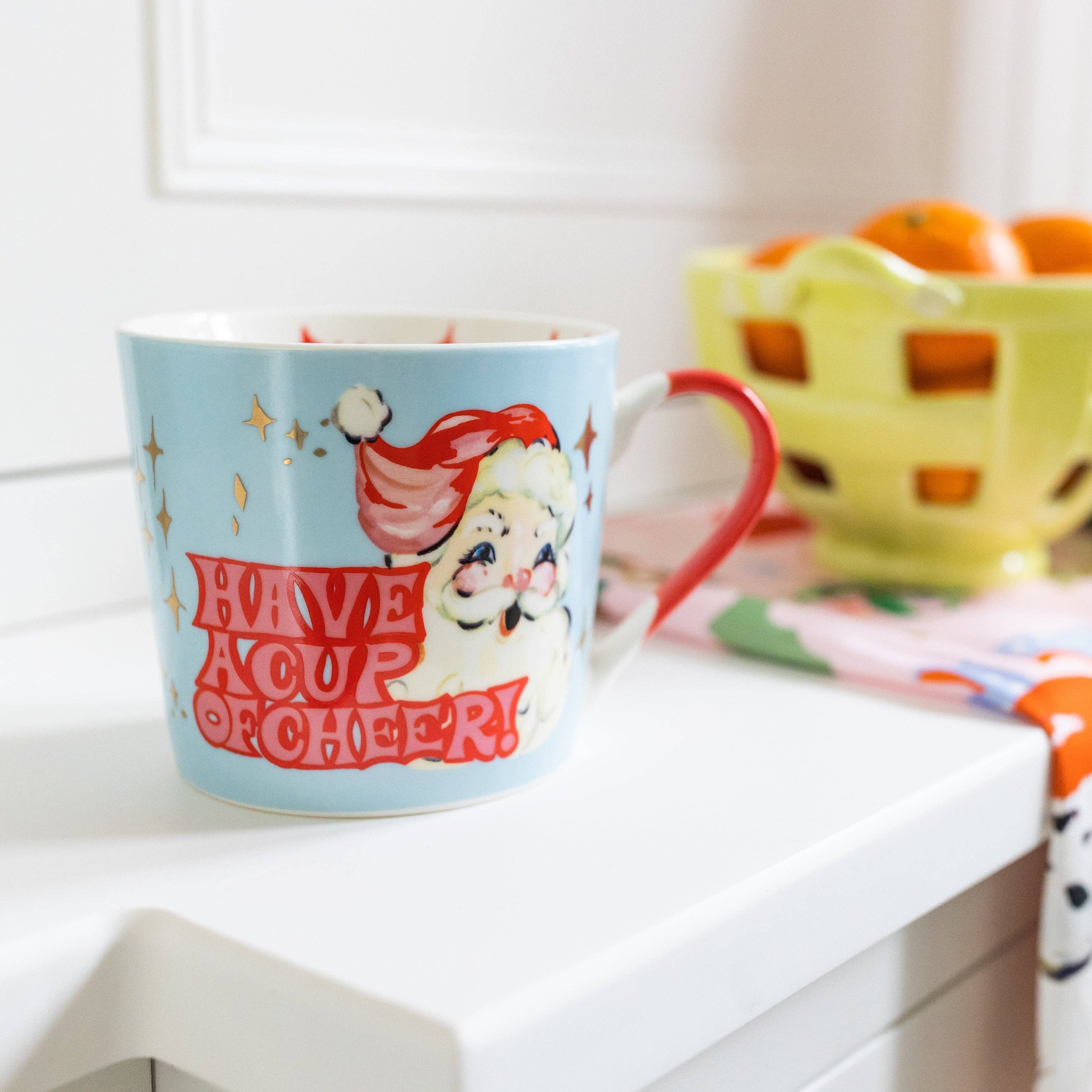 Mug with a vintage design of a cartoon character and text 'Have a Cup of Cheer!' on a white surface.