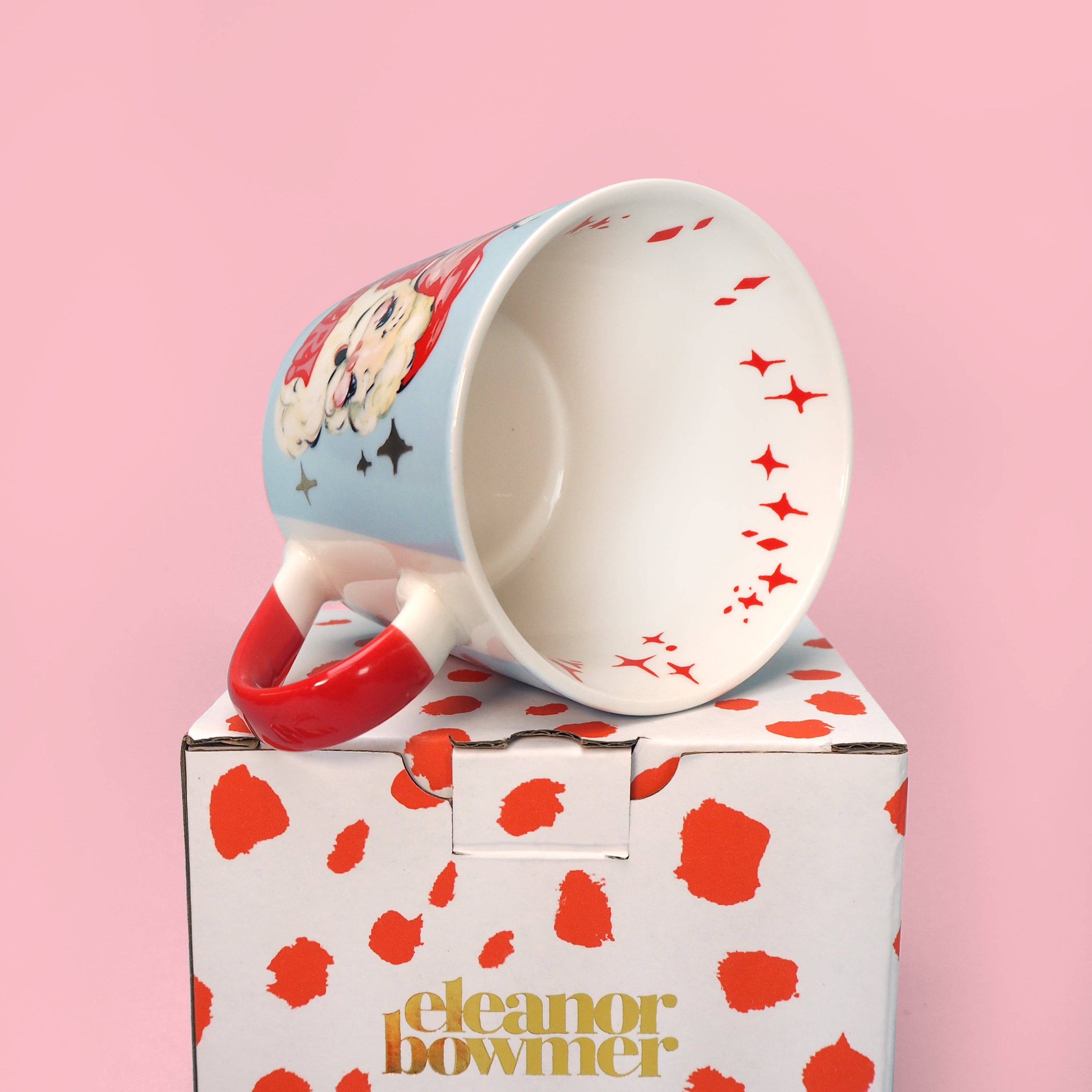 Mug with red handle and design on a pink background, featuring the brand 'Eleanor Bowmer"
