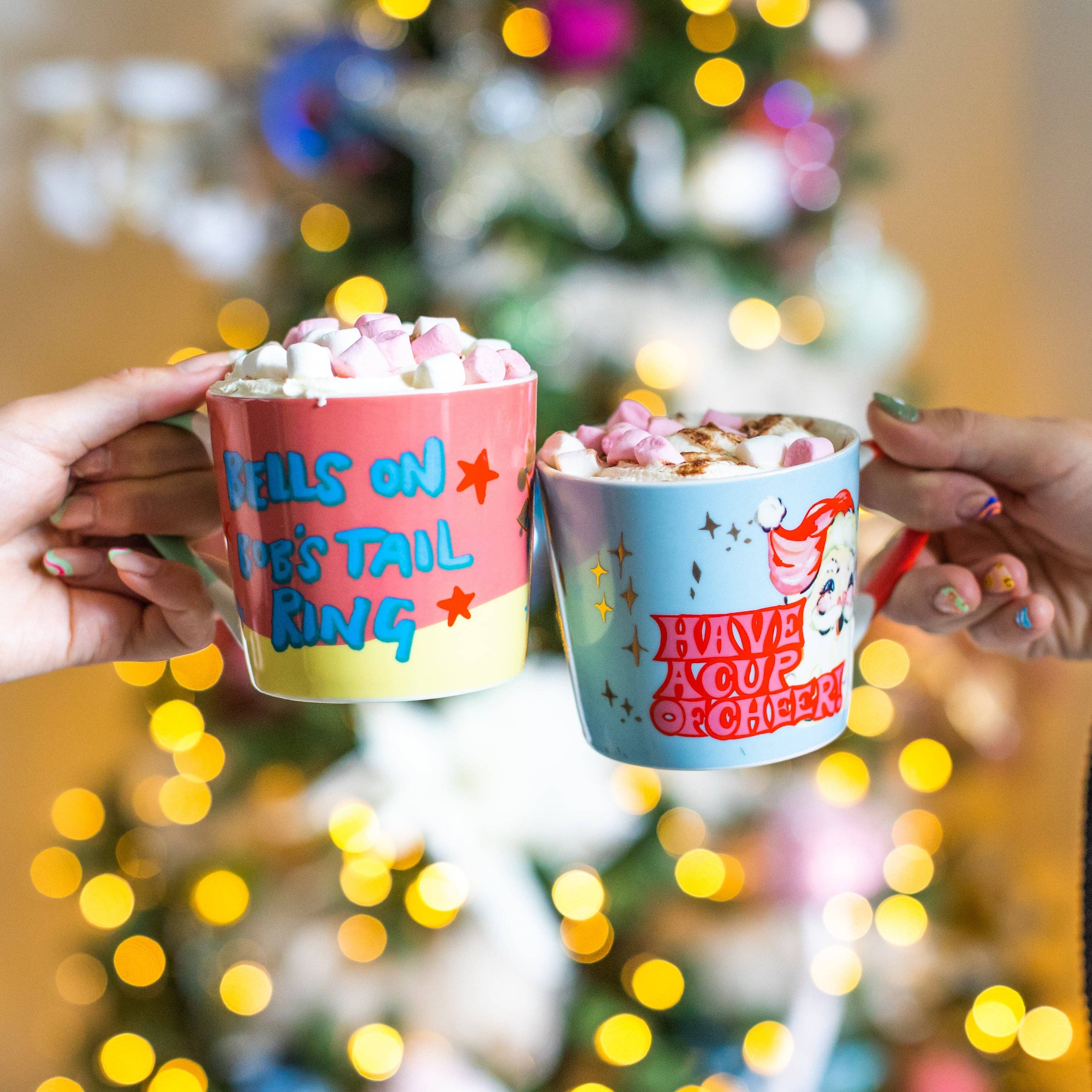Two colourful hot chocolate cups held by hands with a festive background
