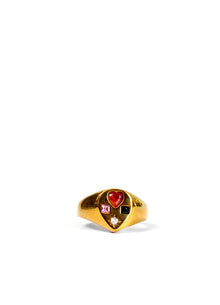 A gold signet ring featuring a teardrop shaped face with a red heart gemstone, a small pink stone, a black square stone, and a tiny clear accent stone, set against a plain white background.