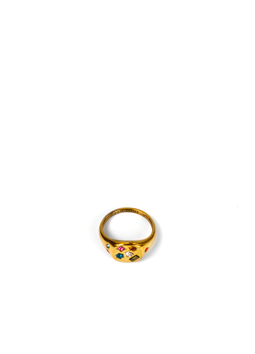 A gold signet ring featuring colorful enamel details and small red gemstones centered on a plain white background.