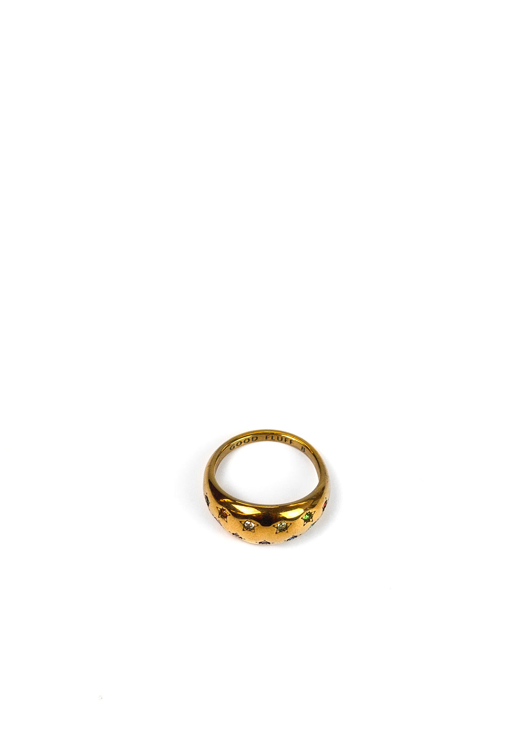 A gold band ring with a textured, raised pattern of small dark stones, photographed on a seamless white background.
