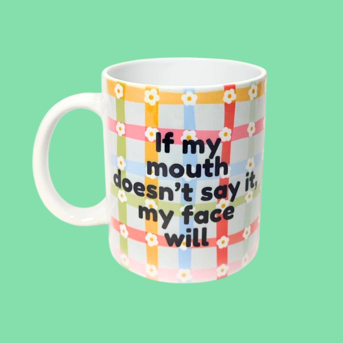 Mug with colorful plaid pattern and text on a green background