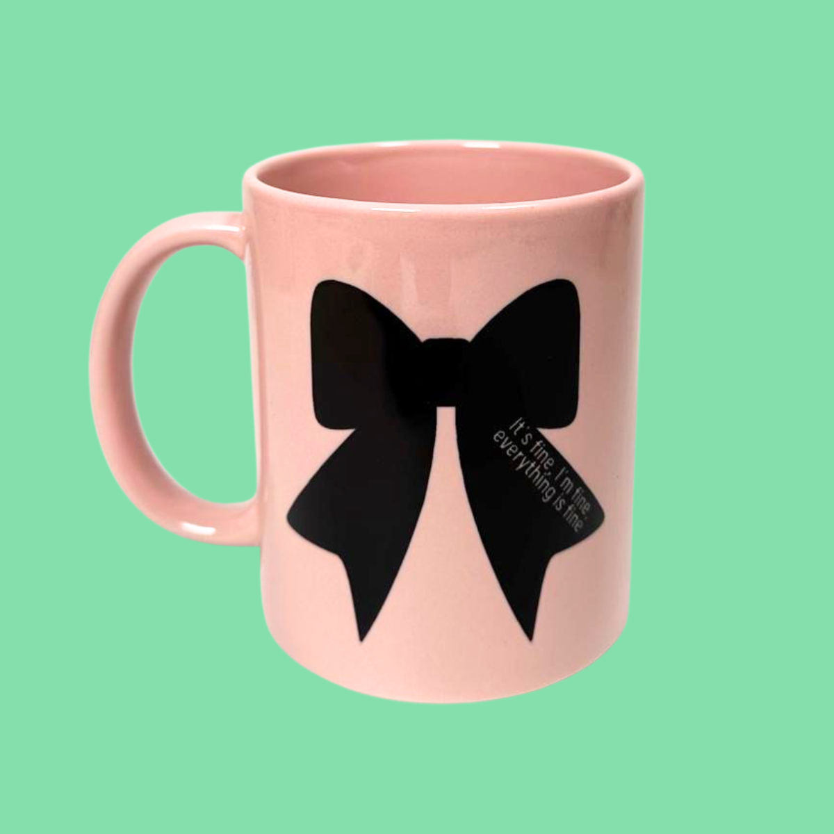 Pink mug with a black bow design on a green background