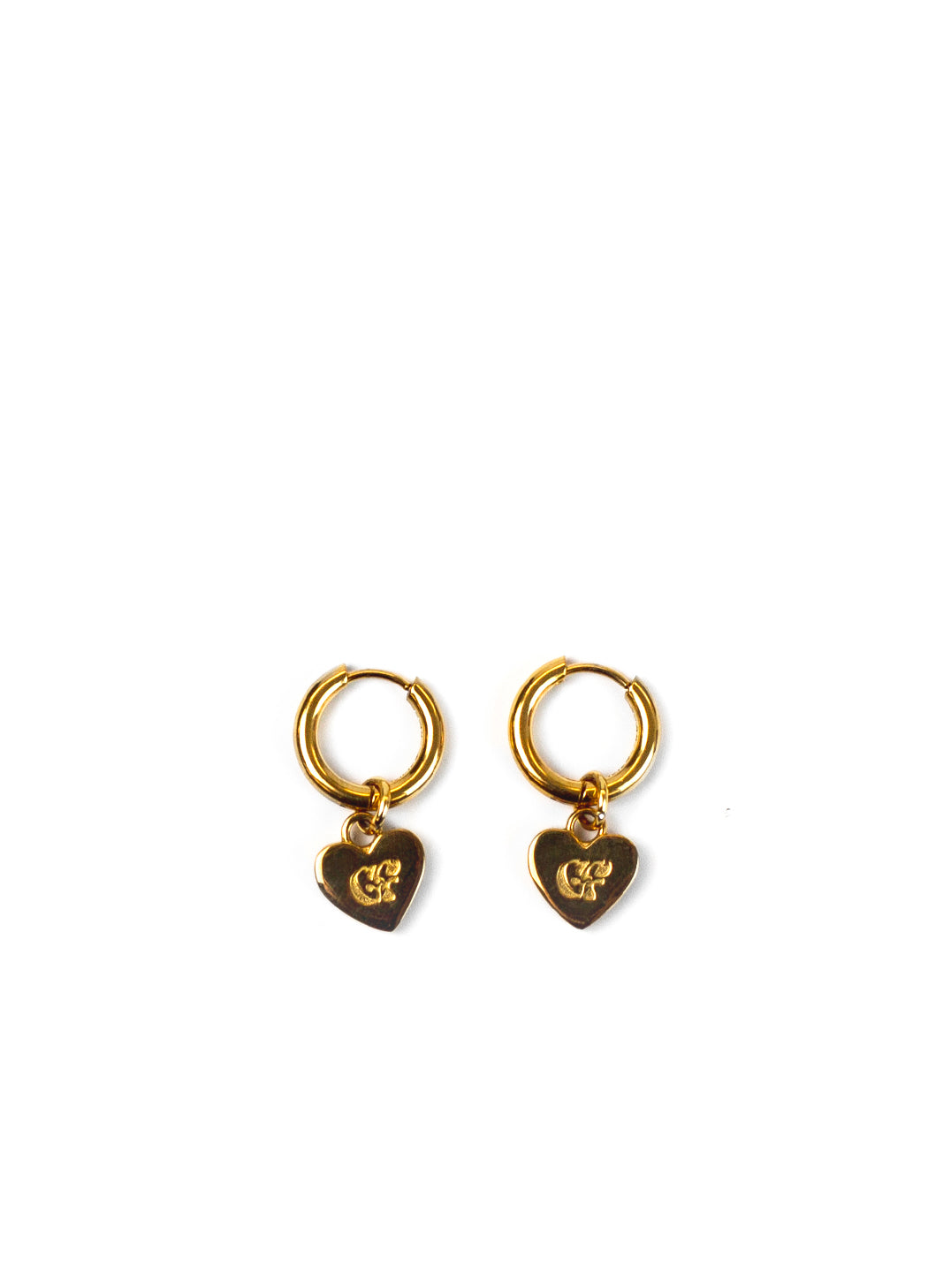 A pair of gold huggie hoop earrings with dangling heart charms featuring an engraved monogram logo, displayed on a clean white background.