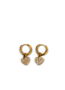 A pair of gold huggie hoop earrings with dangling heart charms encrusted with clear rhinestones, displayed on a clean white background.