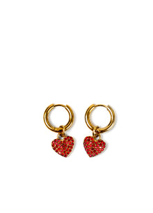 A pair of gold hoop earrings with dangling red rhinestone-encrusted heart charms, displayed on a clean white background.