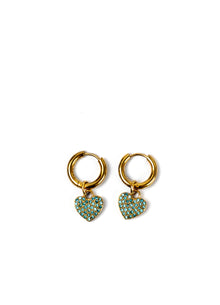 A pair of gold huggie hoop earrings with small dangling heart charms covered in turquoise-colored rhinestones, set against a plain white background.