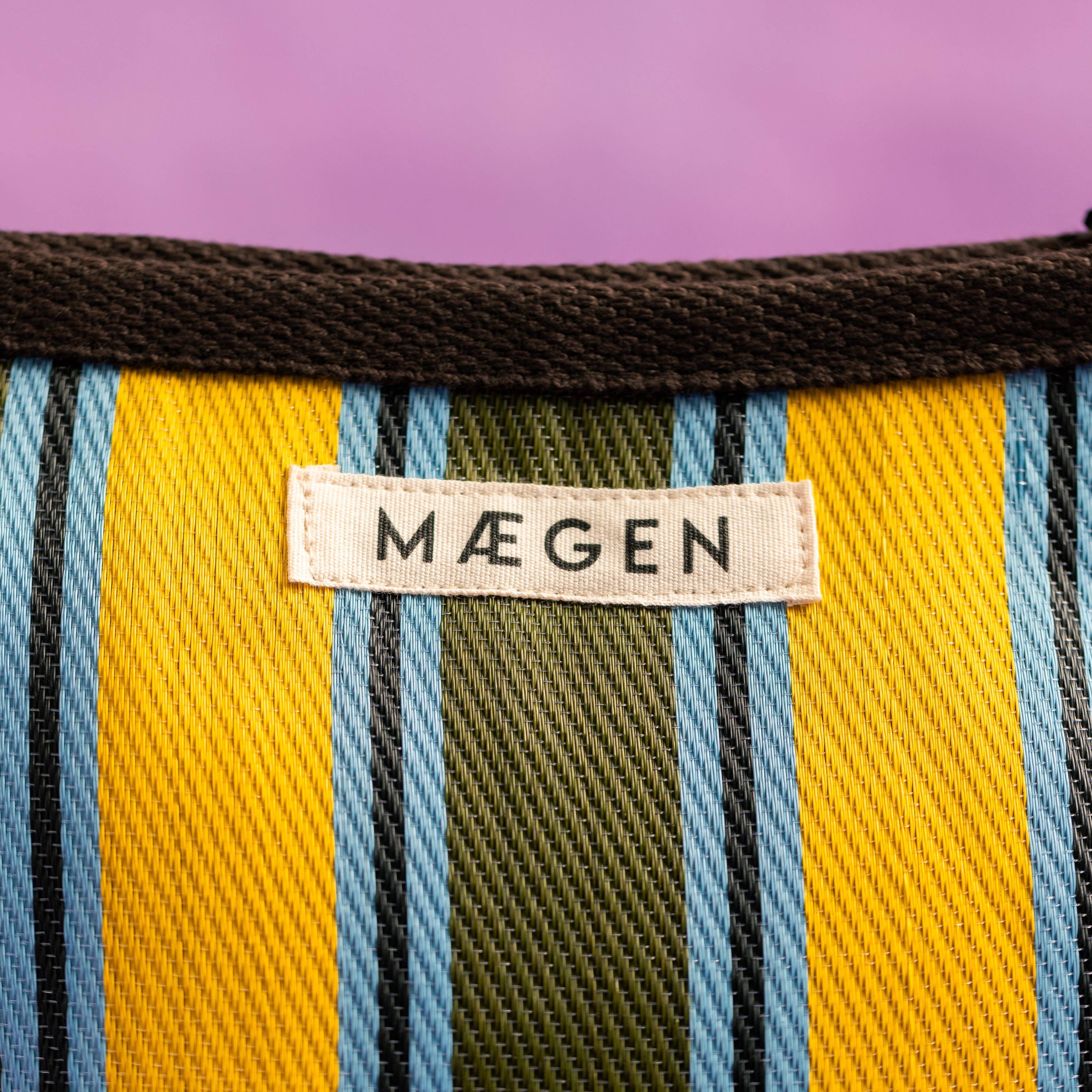 Striped fabric with a 'Máegen' label against a purple background