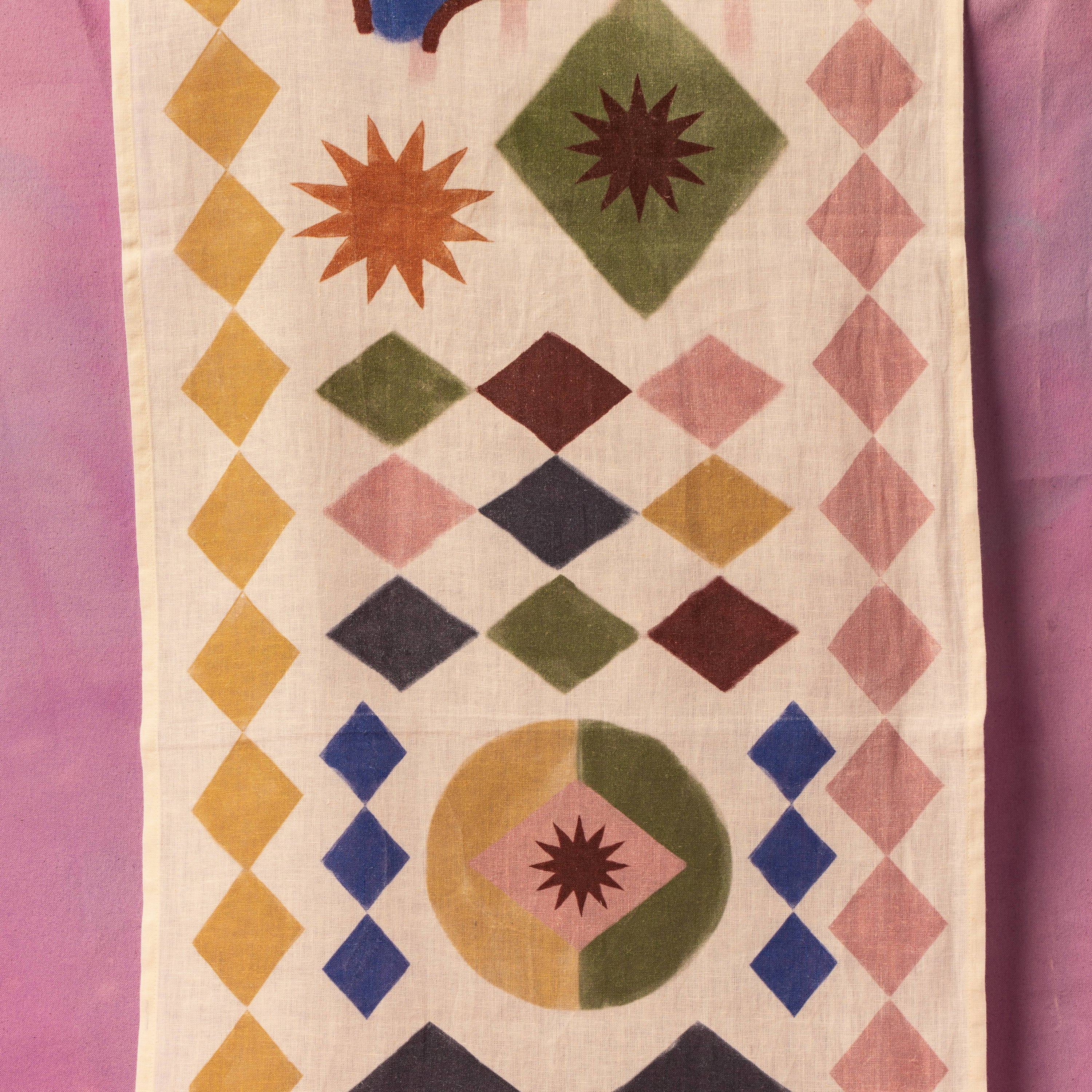 Geometric patterned table runner with colorful diamond shapes on a pink background