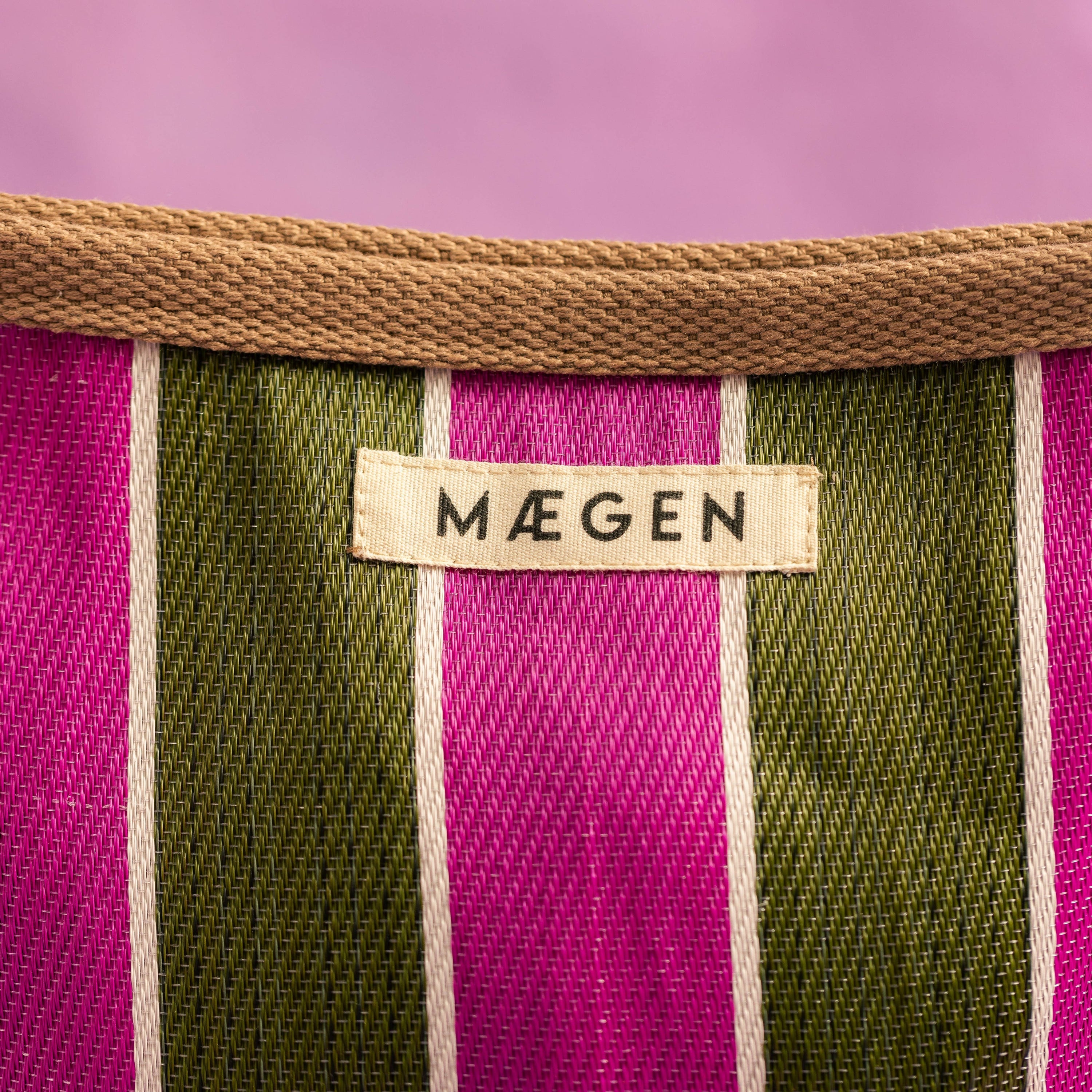 Close-up of a striped fabric with a 'Mäegen' label on a purple background