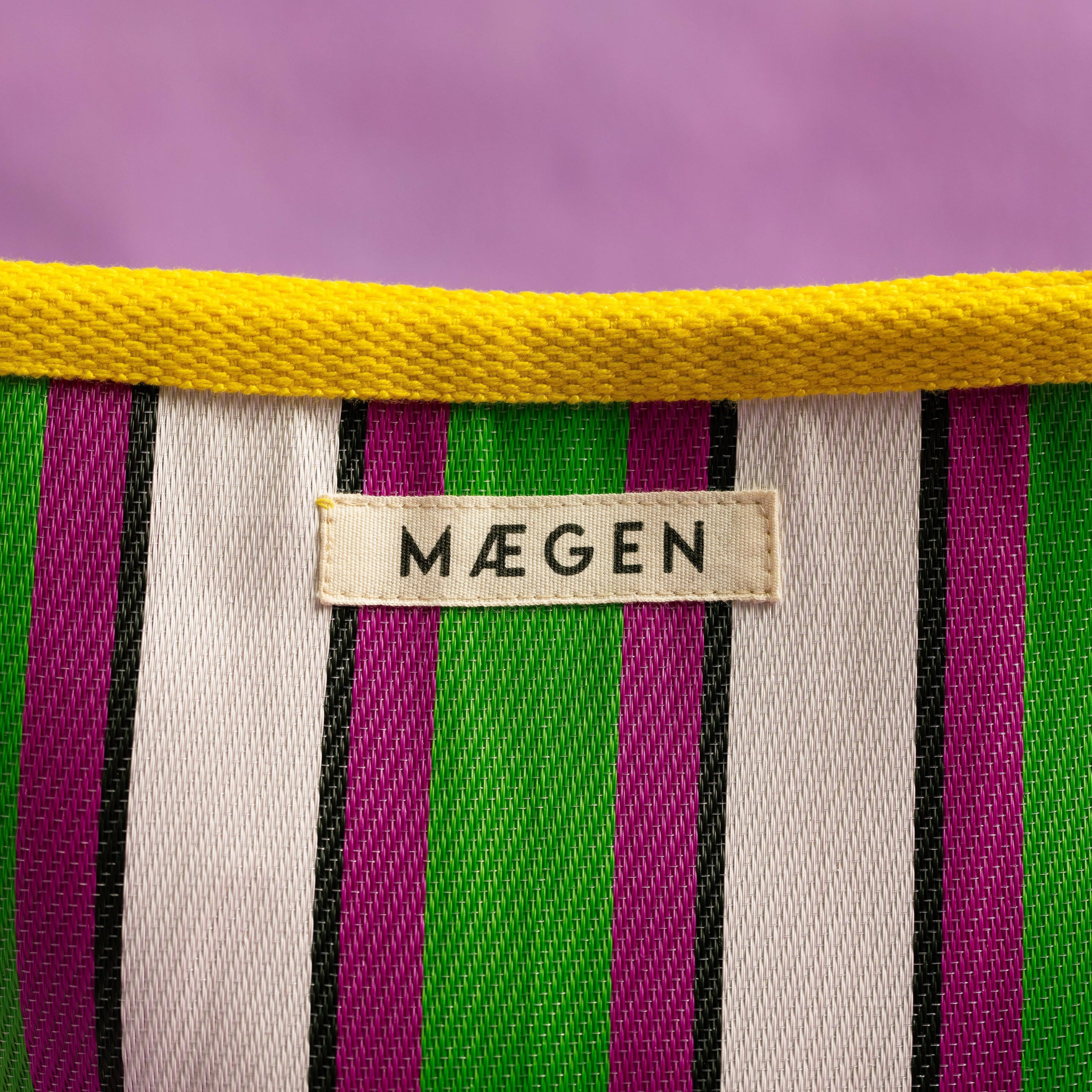 Striped fabric pouch with a 'Máegen' label on a purple background