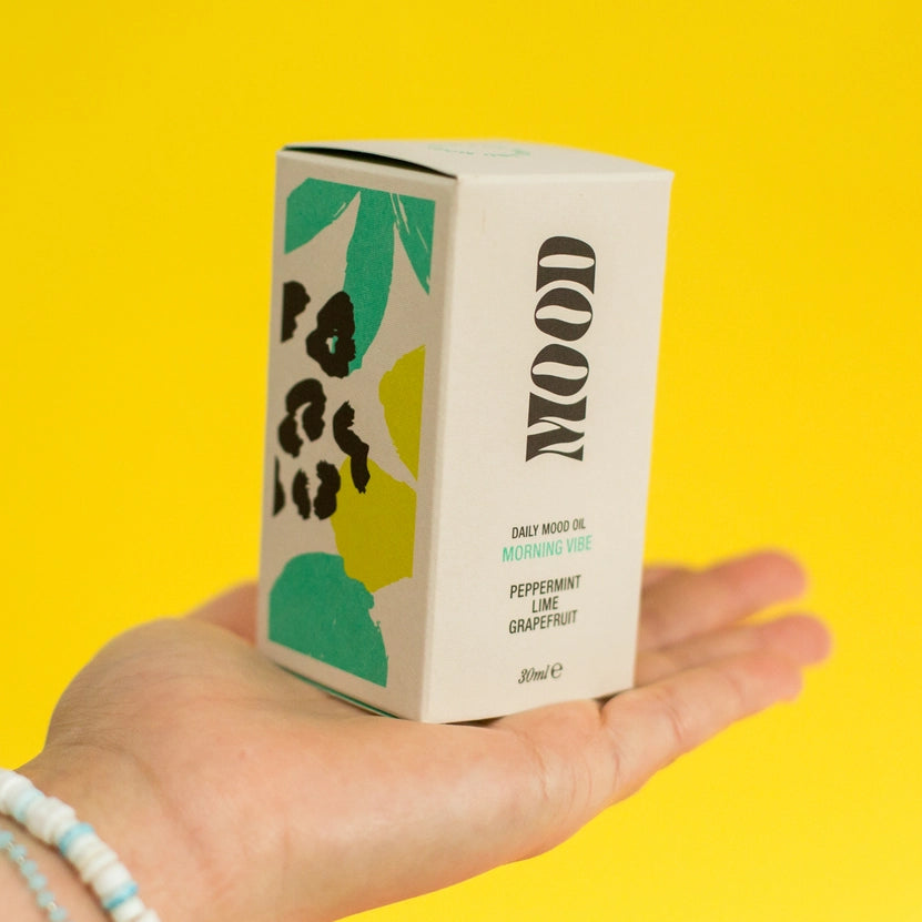 Hand holding a box labeled 'MOOD' against a yellow background