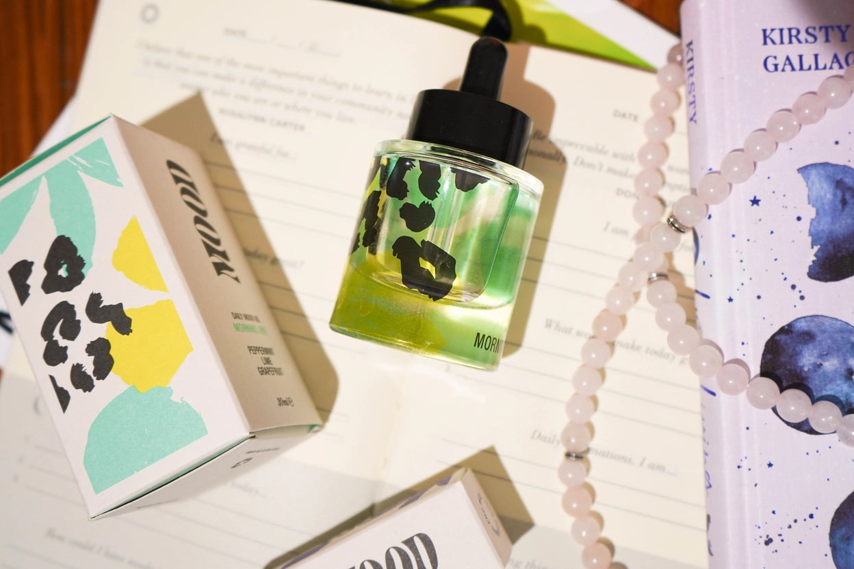 Glass bottle with black dropper on a surface with a box and book in the background