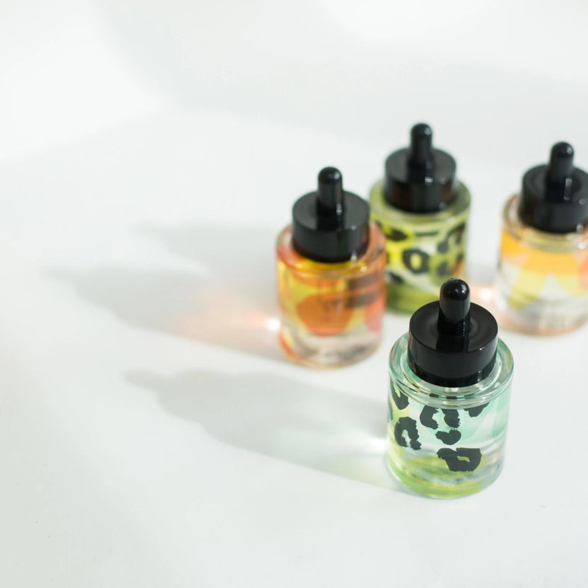 Four small bottles with leopard print designs on a white background