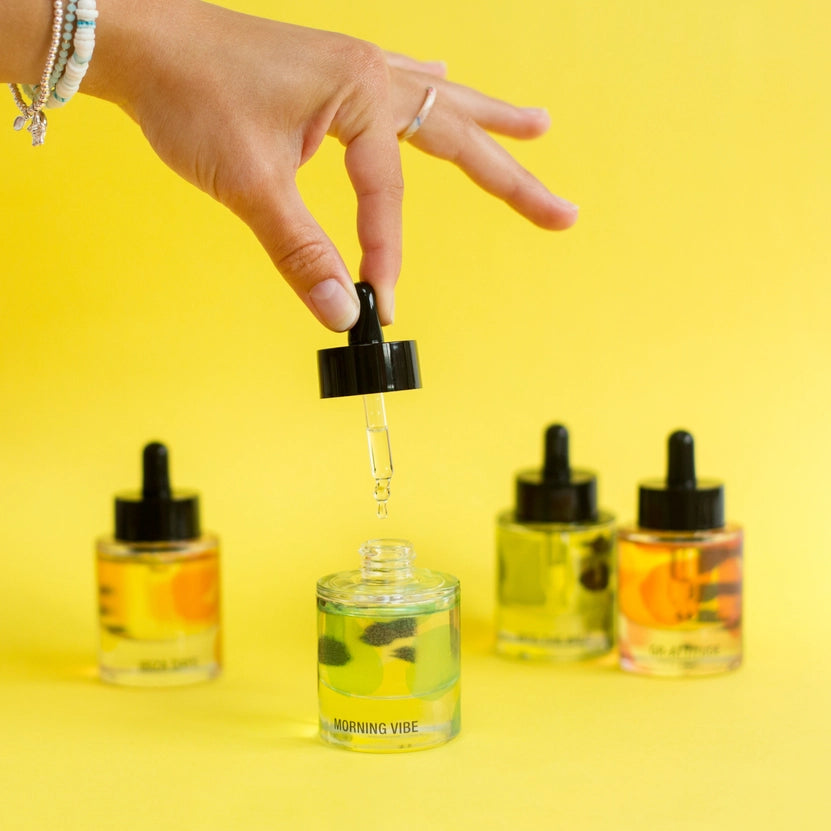 Hand with a dropper bottle of a yellow liquid against a yellow background