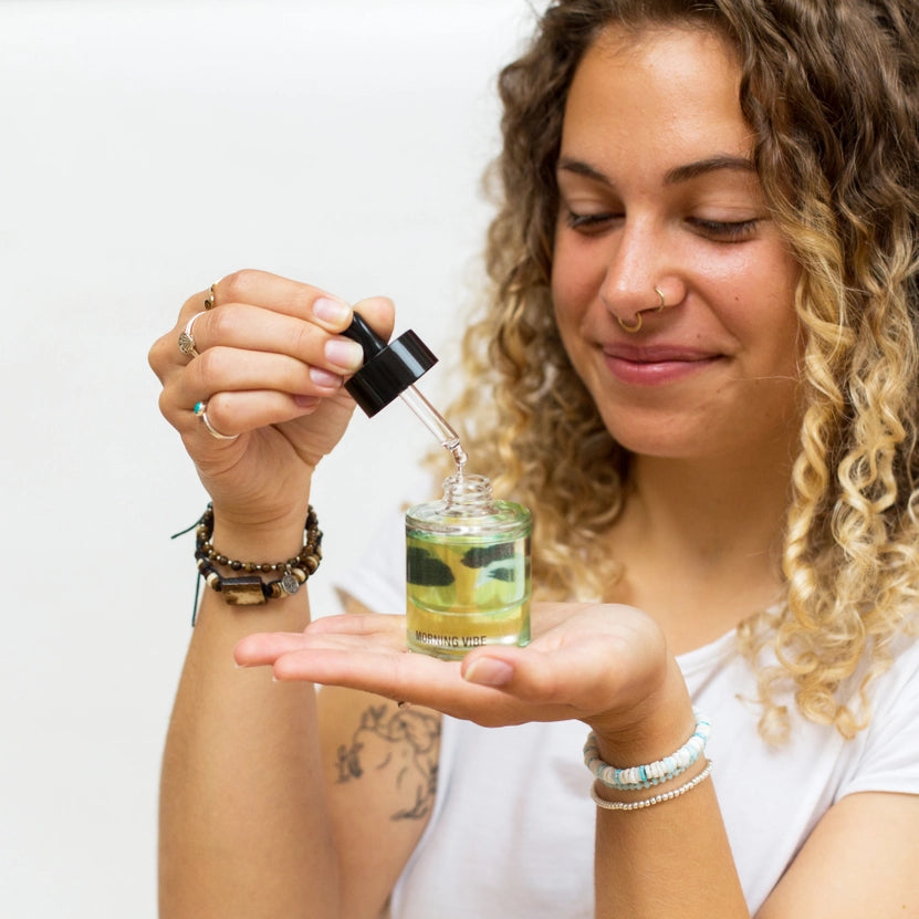 Woman holding a small bottle with a dropper, showing a close-up of the product.