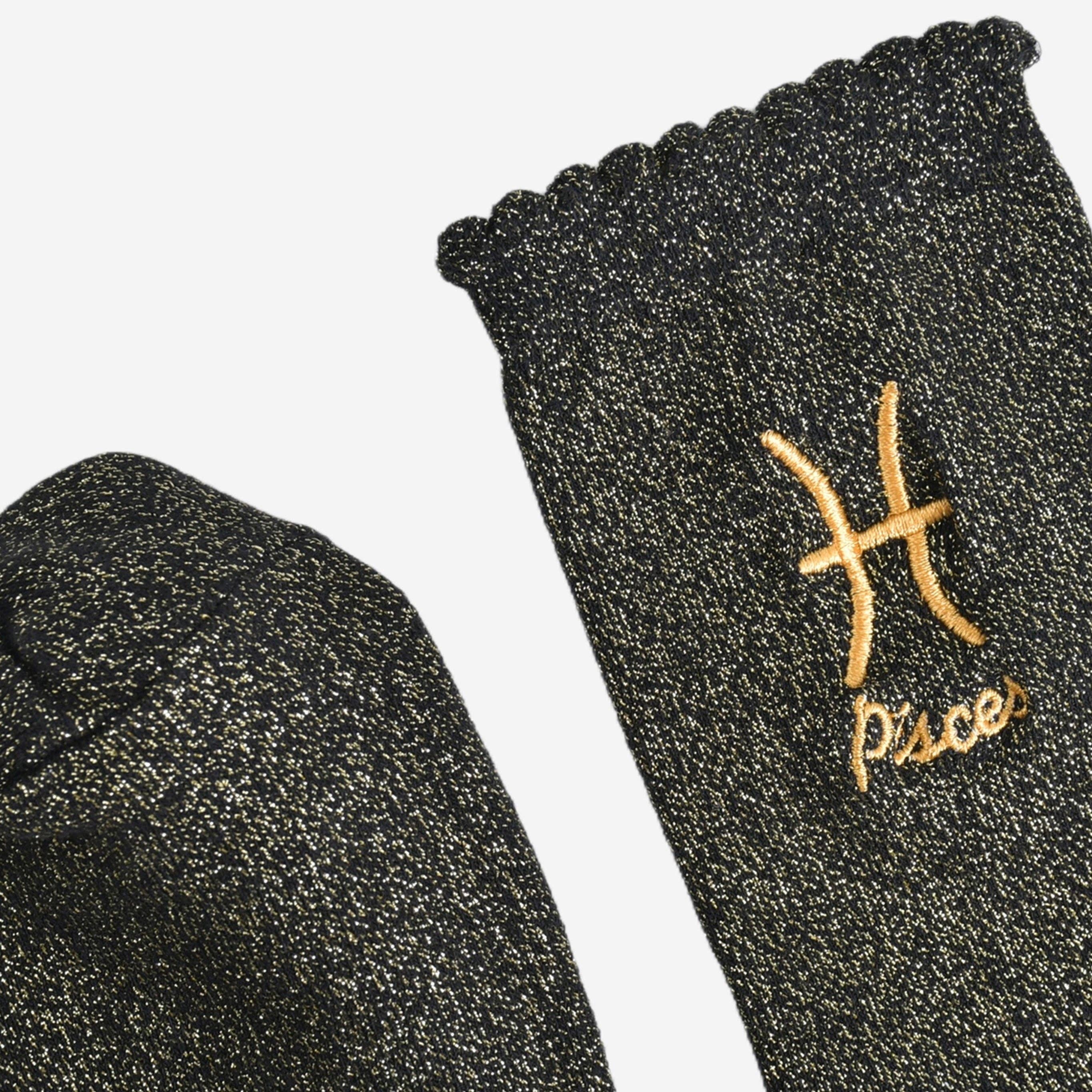 Black socks with gold embroidered Pisces symbol on a white background