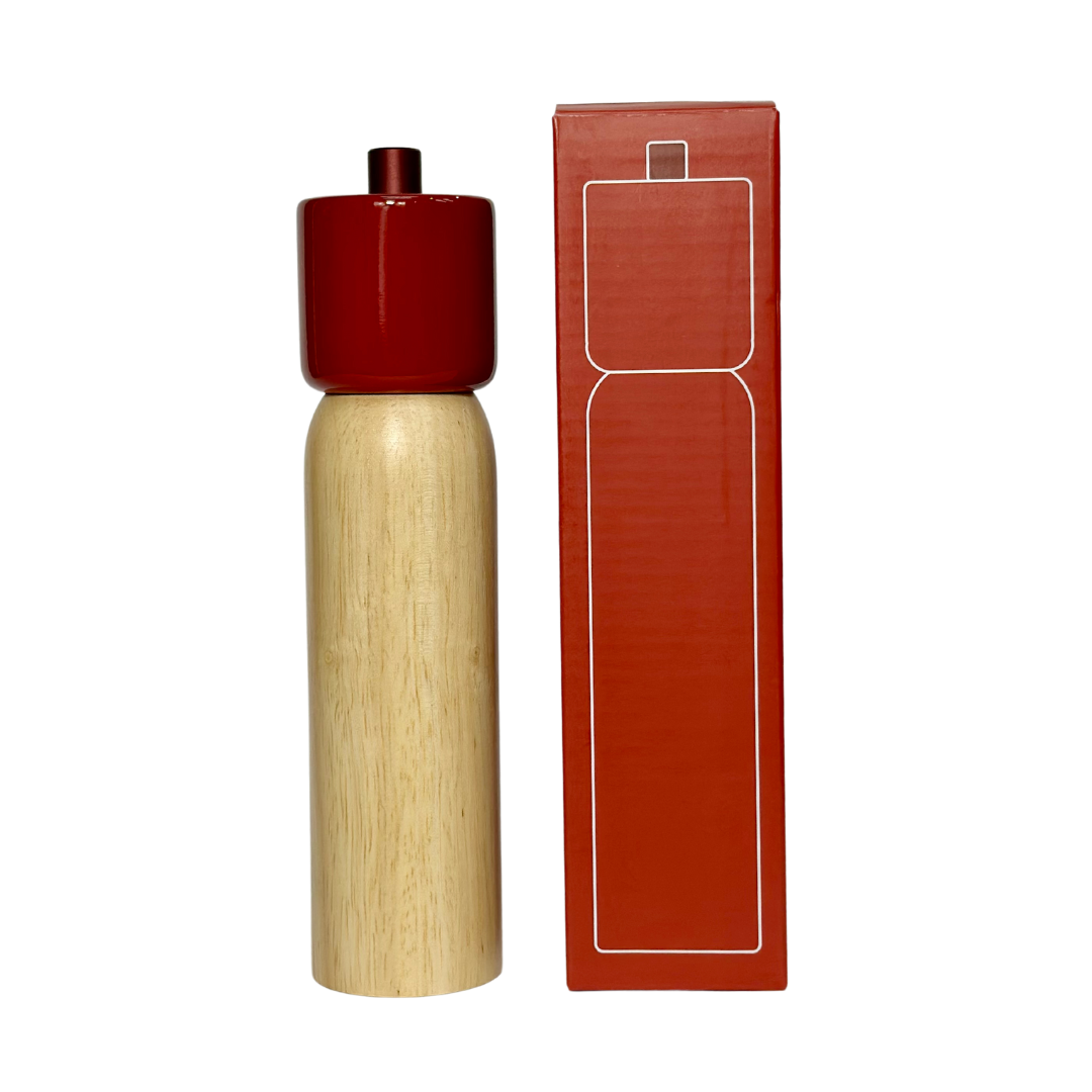 Wooden pepper grinder with red top and matching packaging on a white background