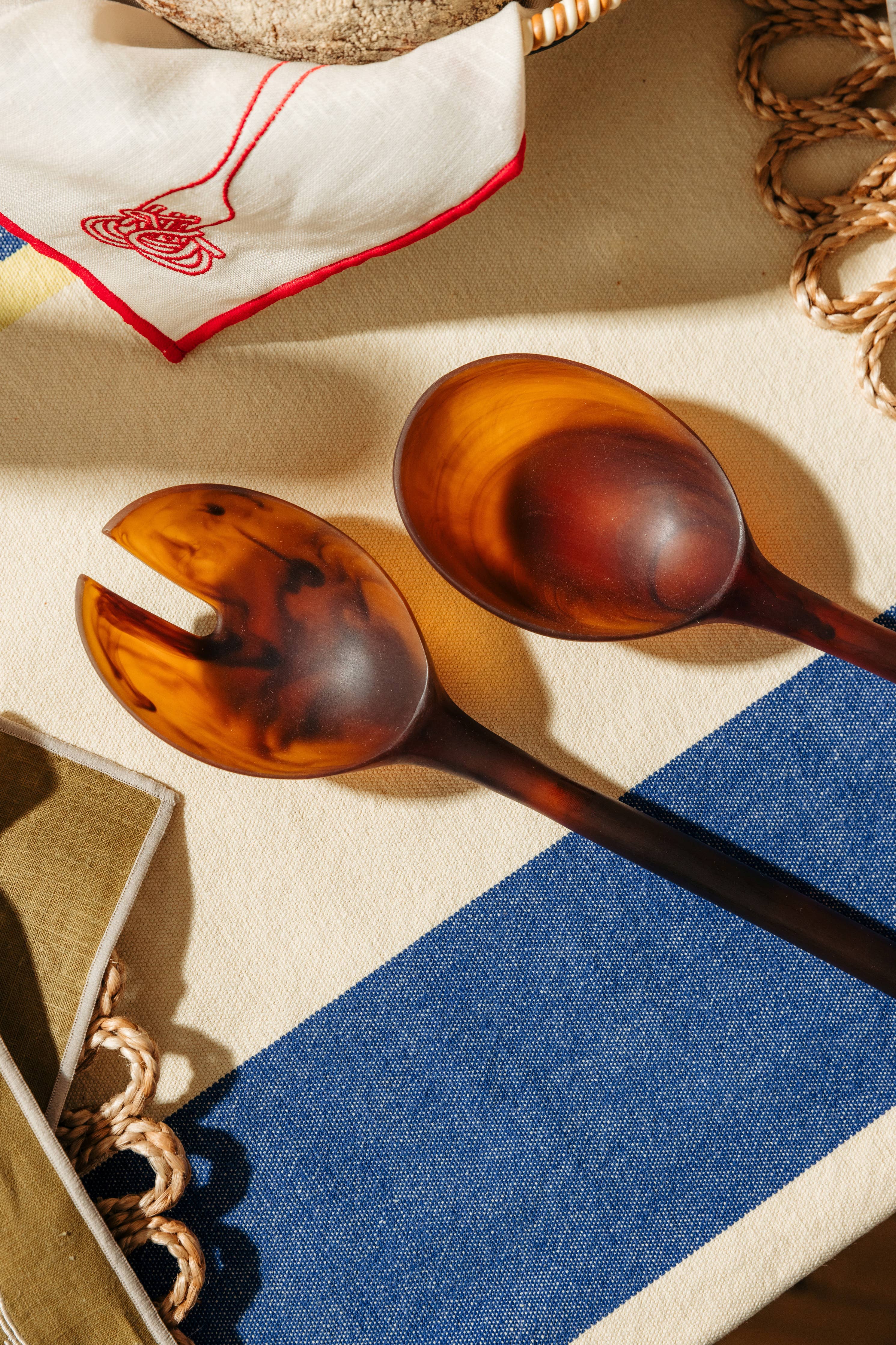 Two tortoiseshell spoons on a textured surface with a blue and beige pattern.