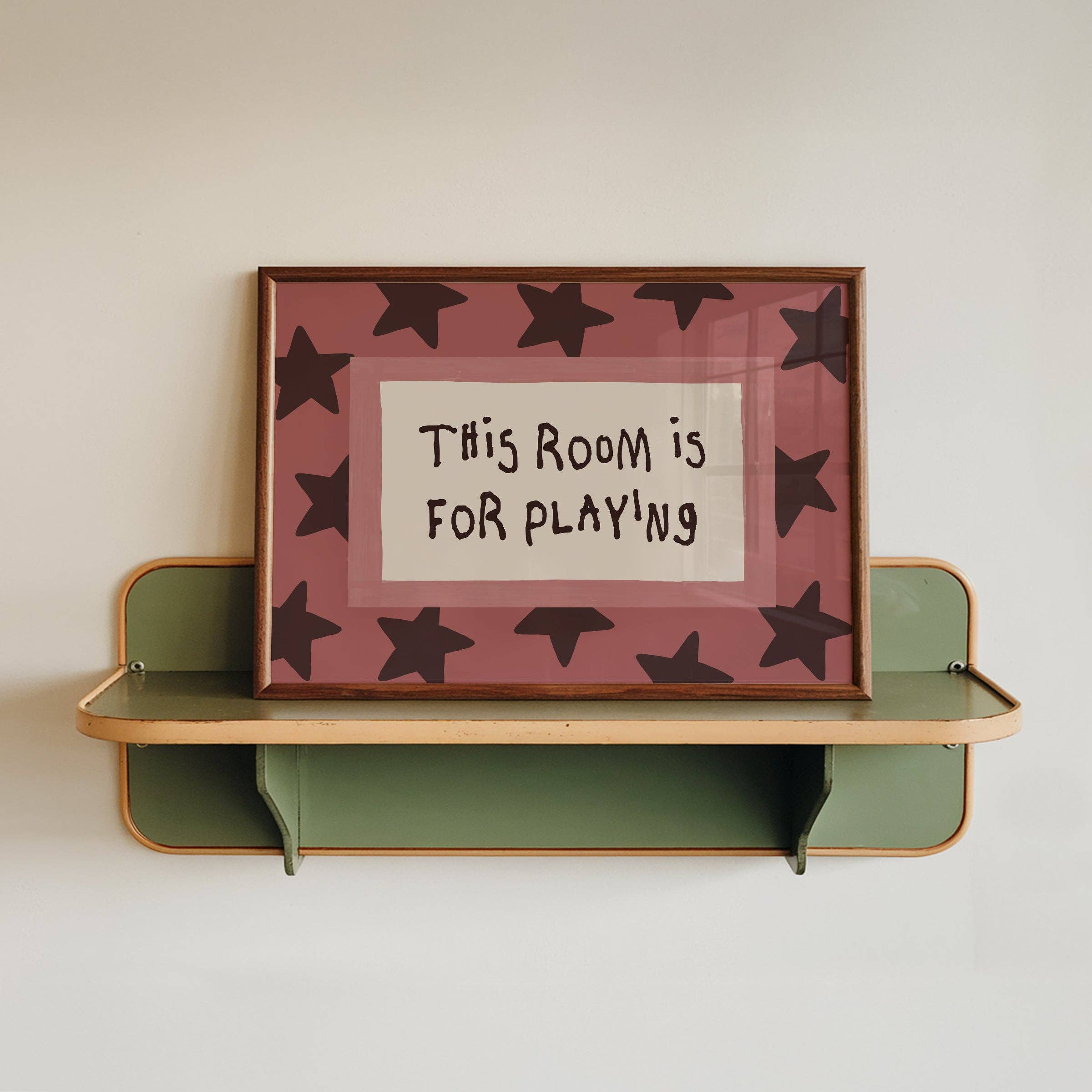Shelf with a framed picture saying 'This Room is for Playing' on a plain background.