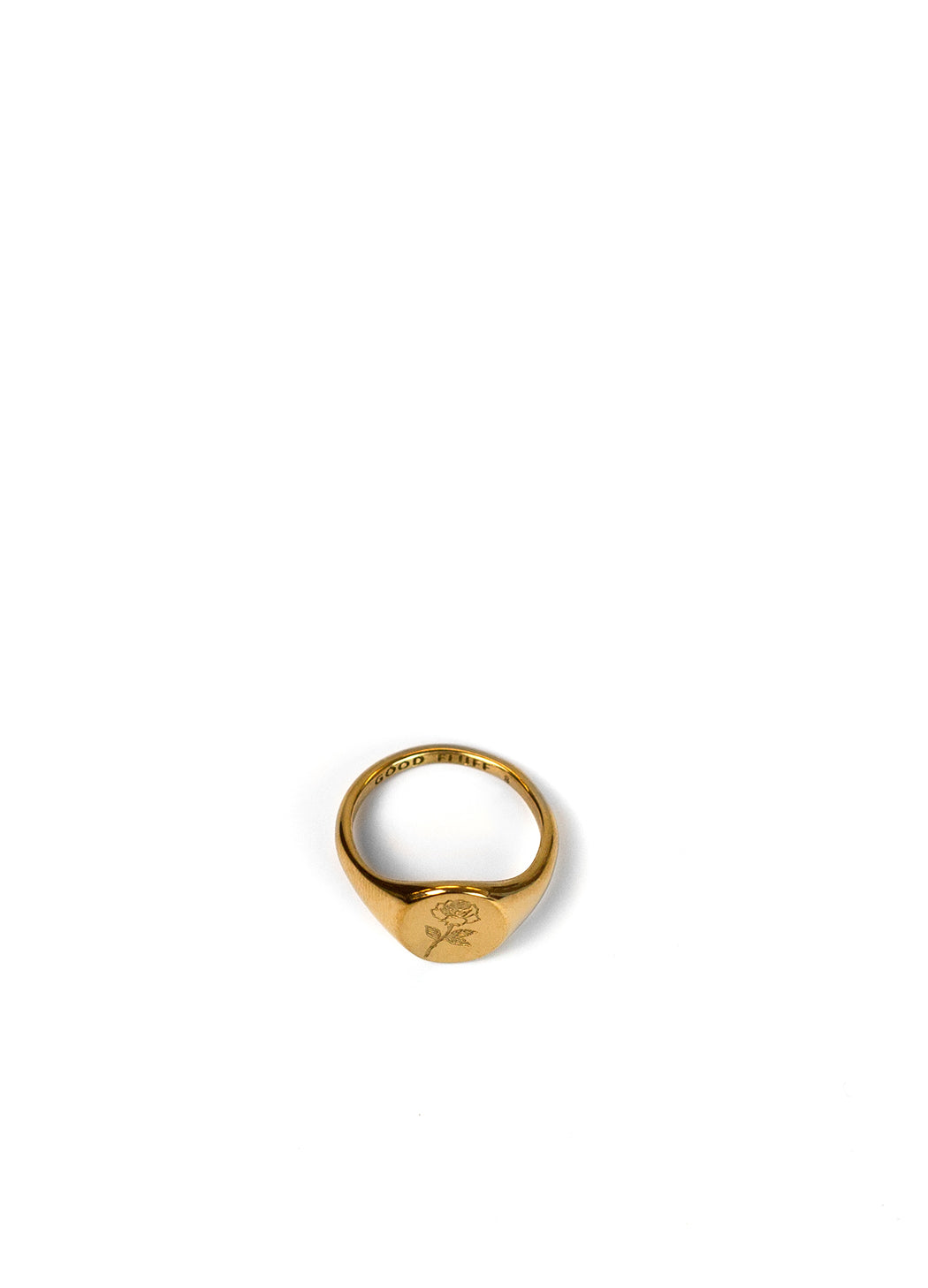 A gold signet ring with an engraved rose motif on the face, photographed on a clean white background.