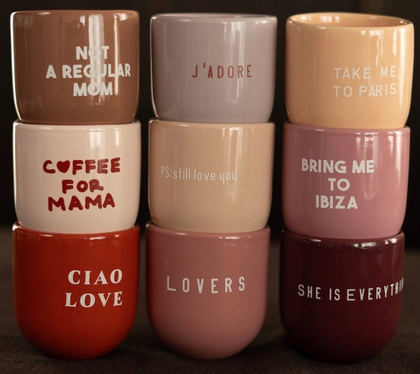 Stack of colorful mugs with various phrases printed on them.