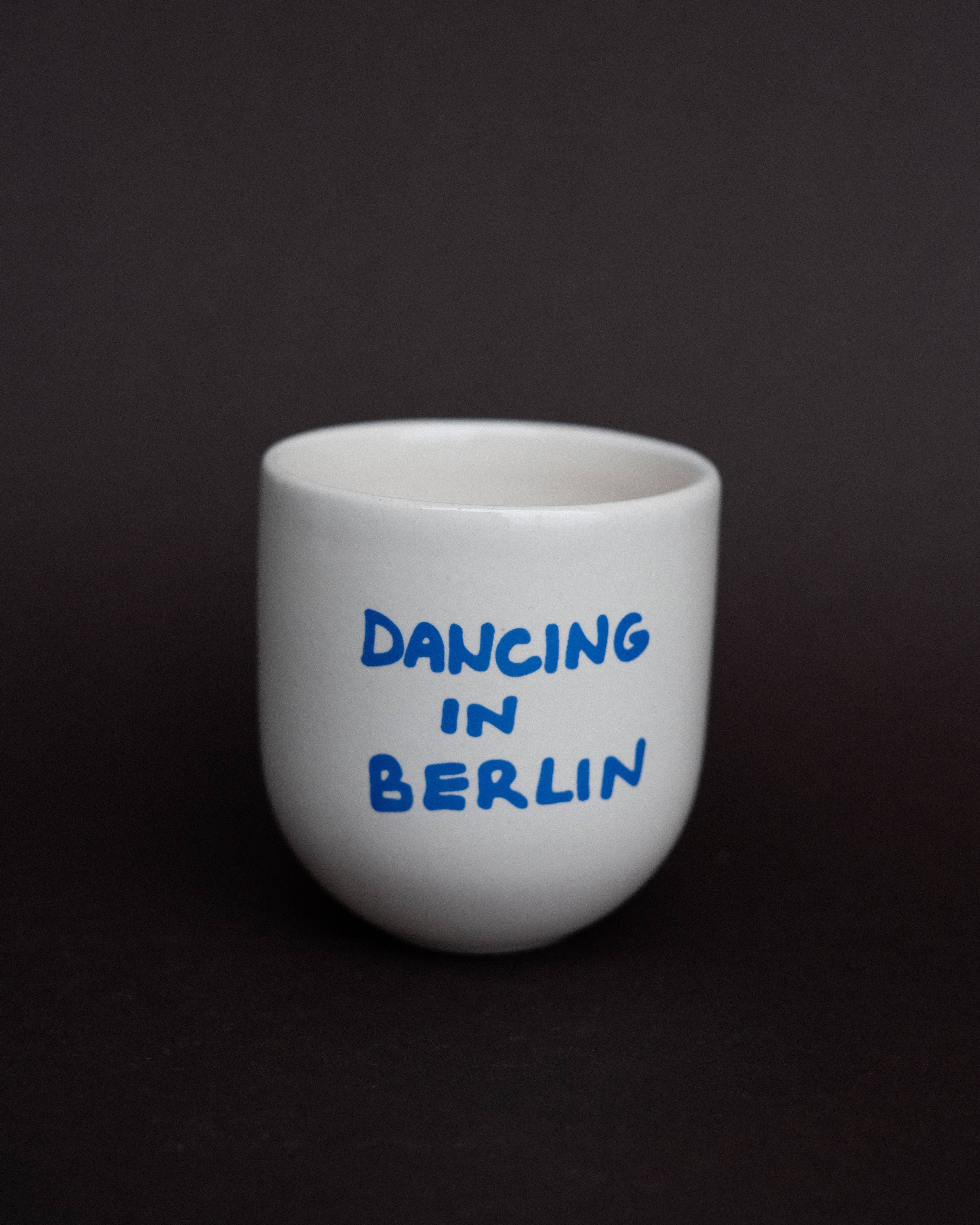 White mug with 'Dancing in Berlin' text on a black background