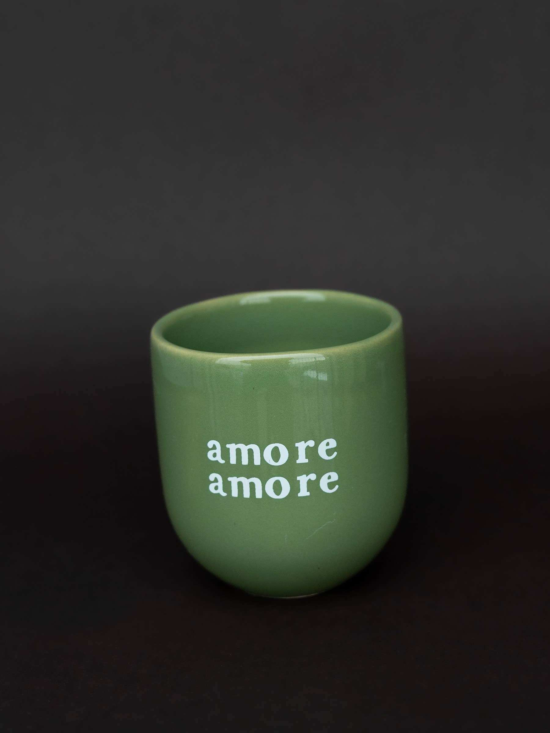 Green mug with 'amore amore' text on a dark background