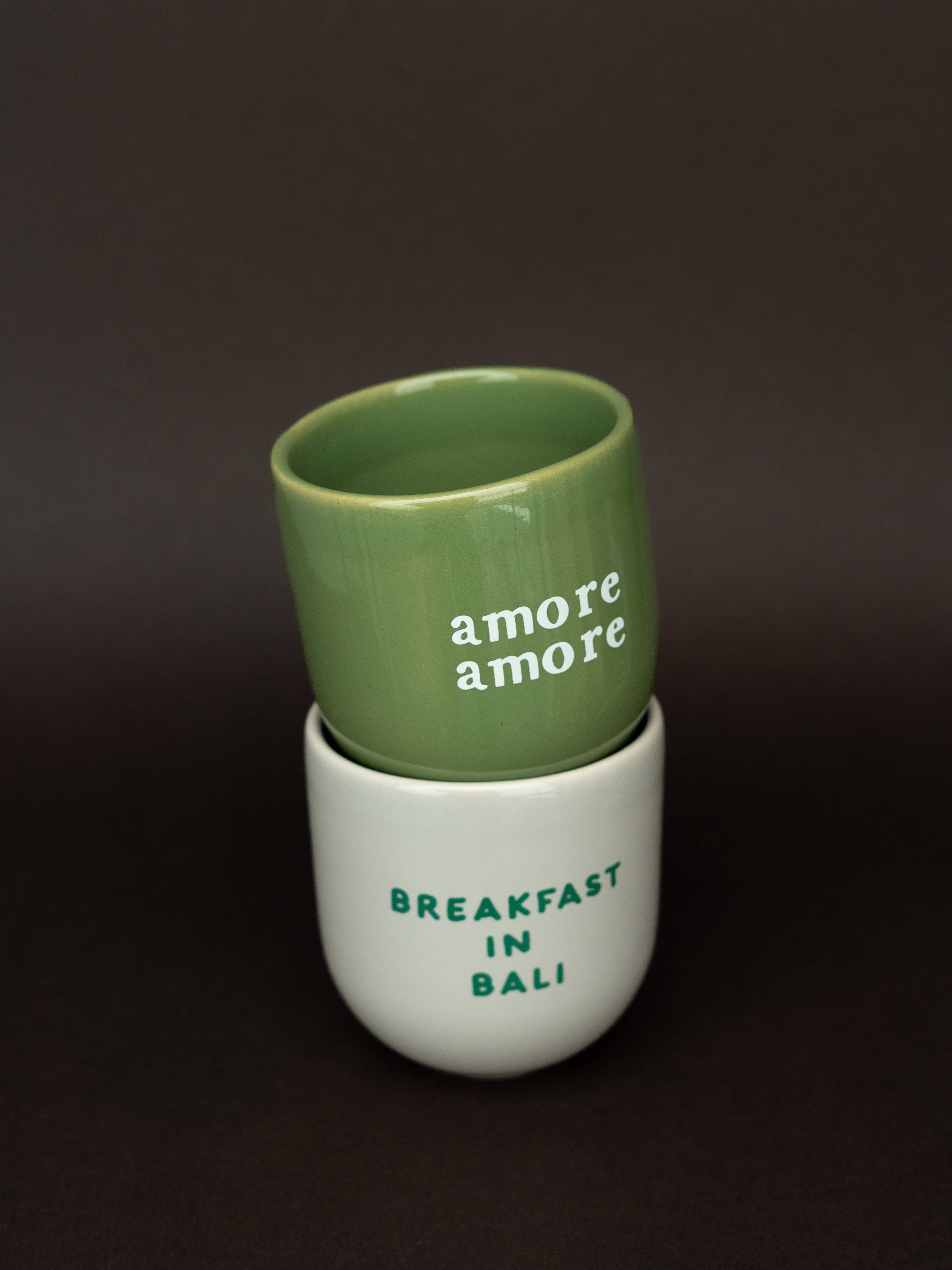 Green and white ceramic cup with 'amore amore' text on a dark background