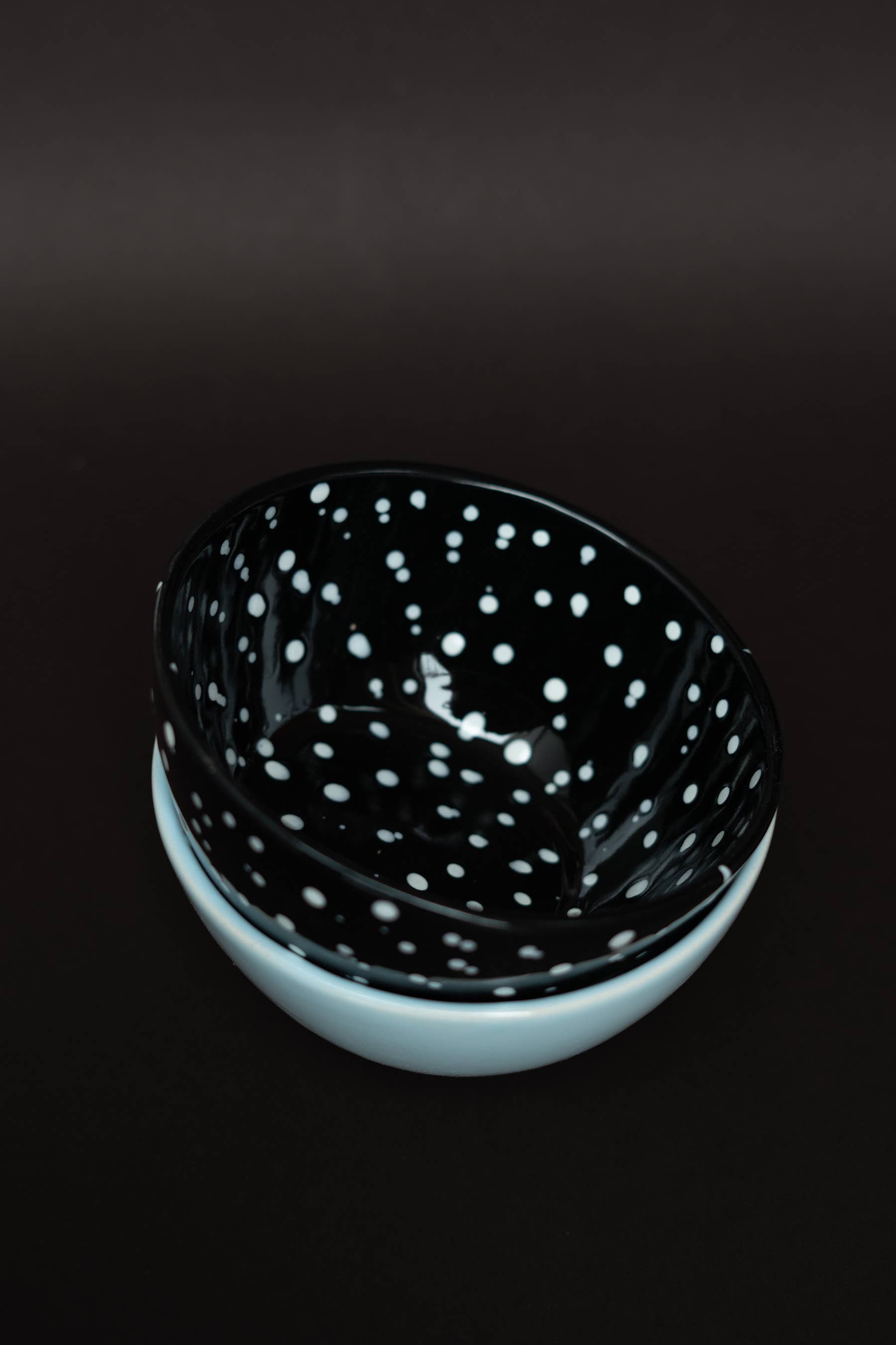 Black ceramic bowl with white speckles on a dark background