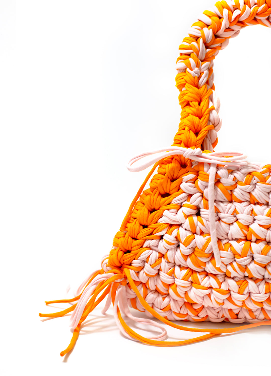 close up of the orange and pink weaved crochet shoulder bag on a white backdrop