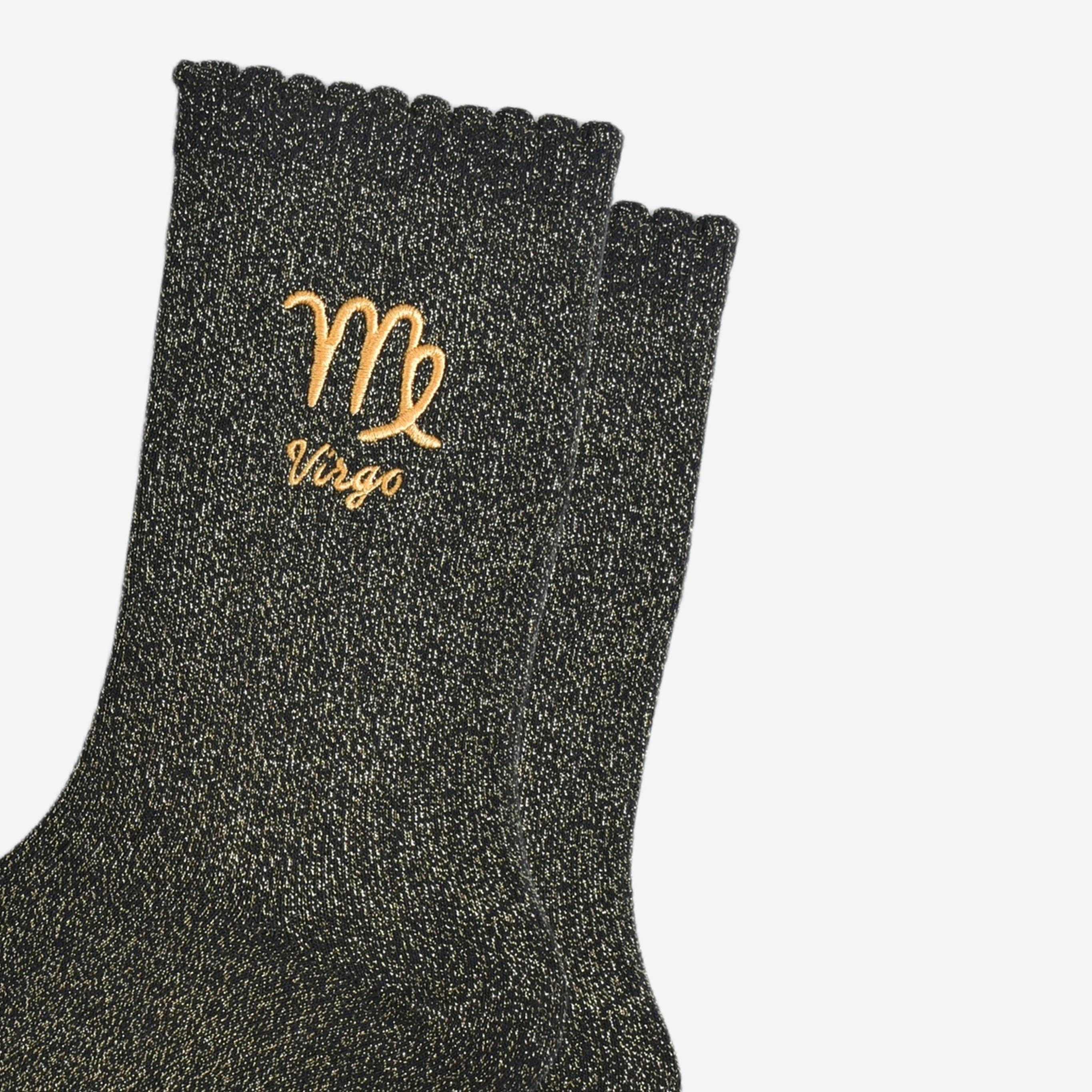 Black socks with gold embroidered 'Virgo' design on a light gray background