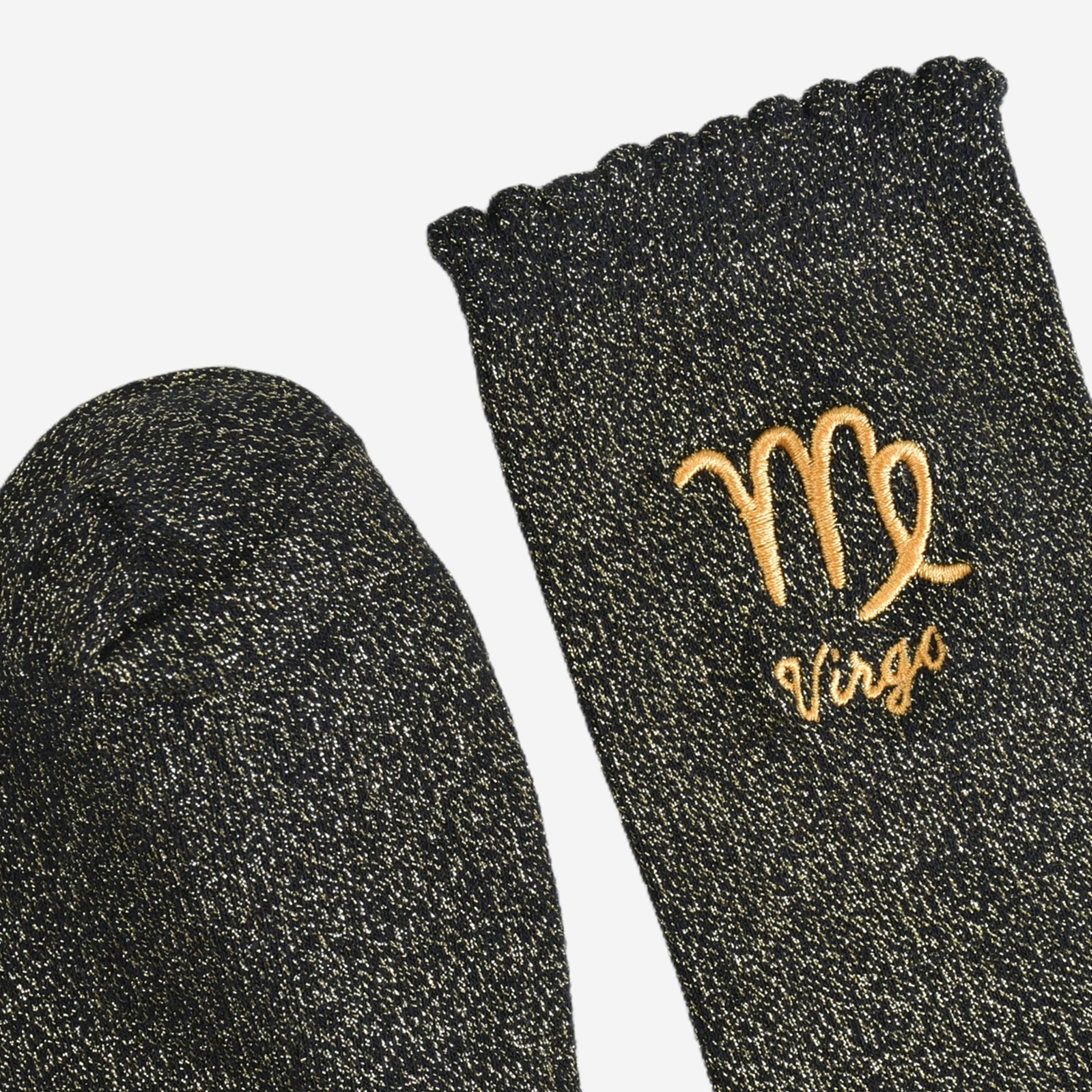 Black glittery sock with 'Virgo' embroidered on it against a white background