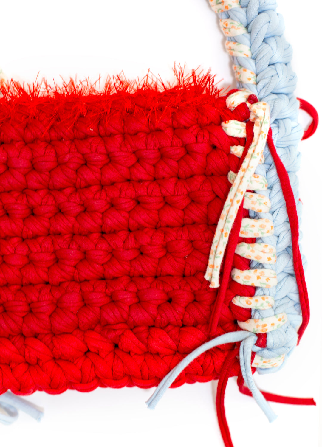 close up shot of the crochet handmade sloe mosey bag, in bright red and sky blue