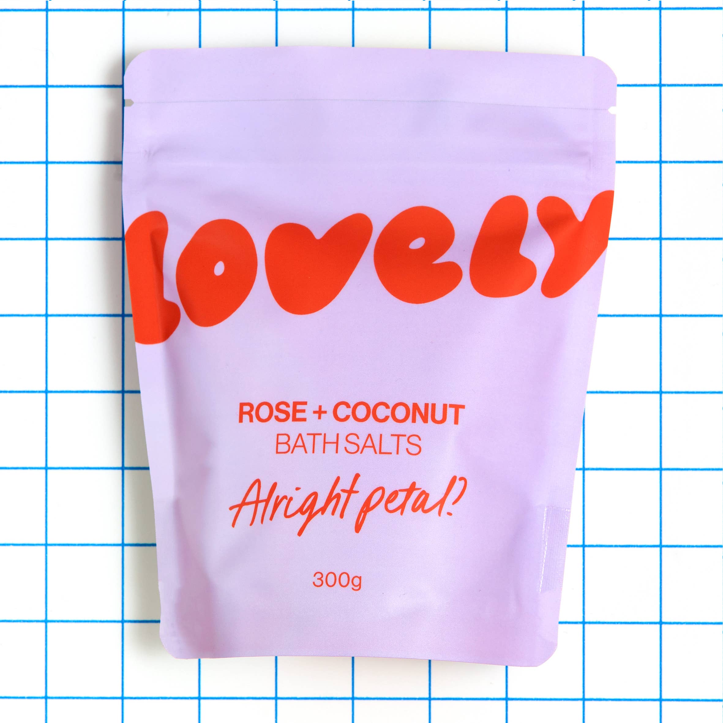 Purple packaging of 'Lovely' rose and coconut bath salts on a grid background
