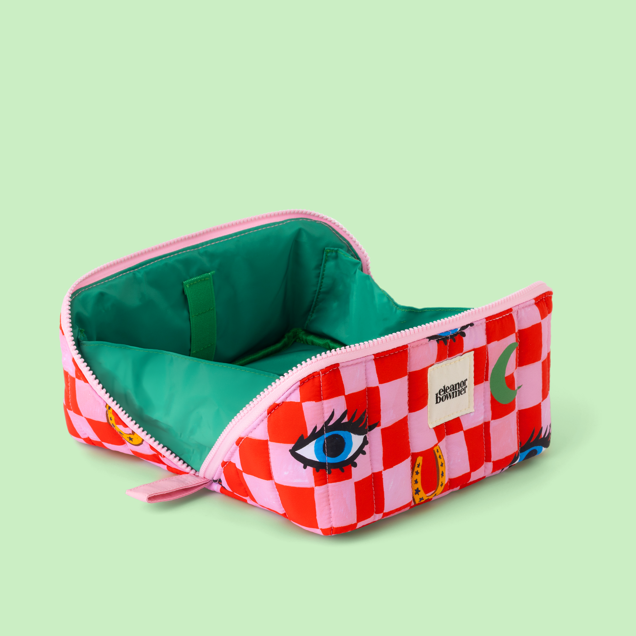 Checkered make up bag opened wide with eye design on a light green background
