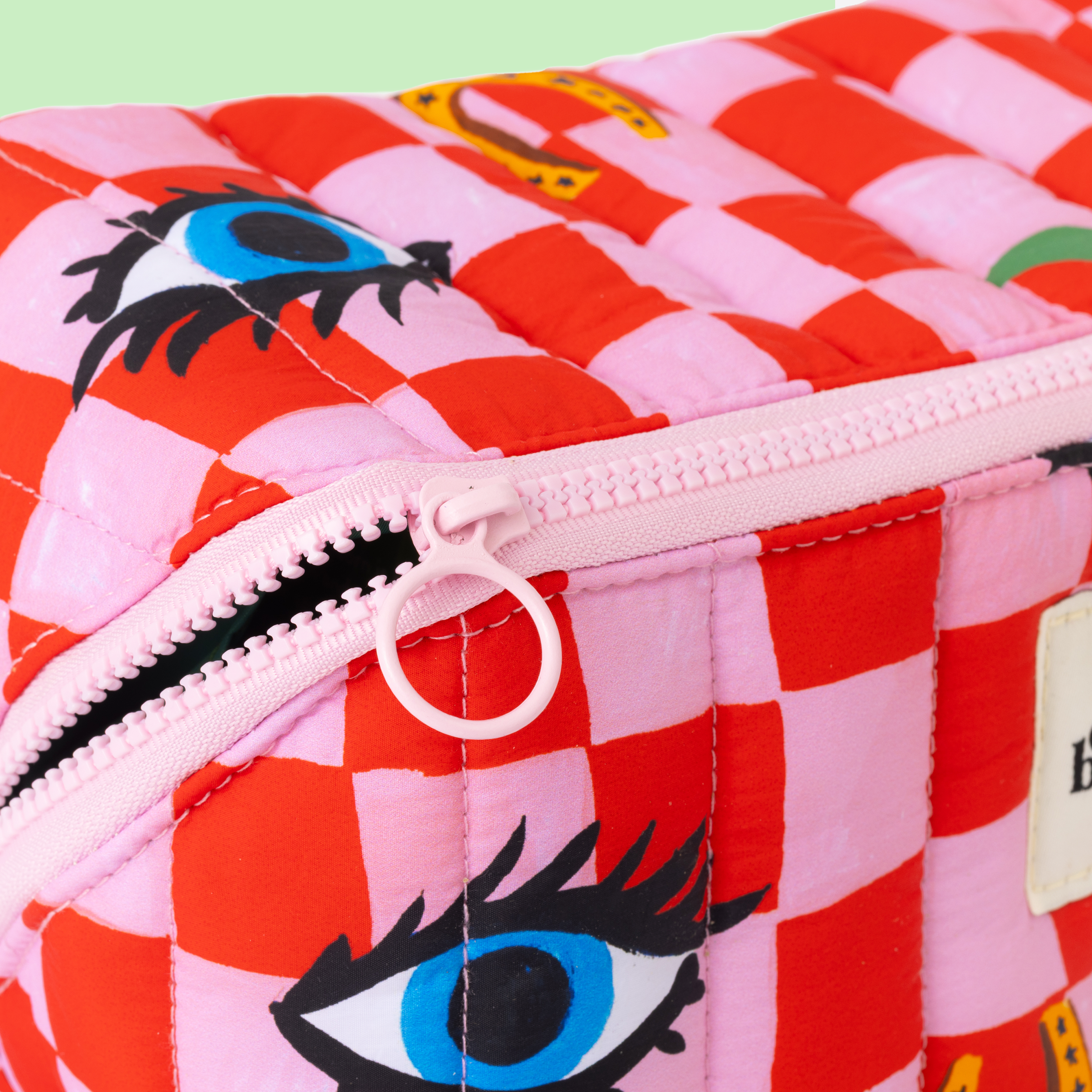 Checkered pouch with eye designs on a pink and red background