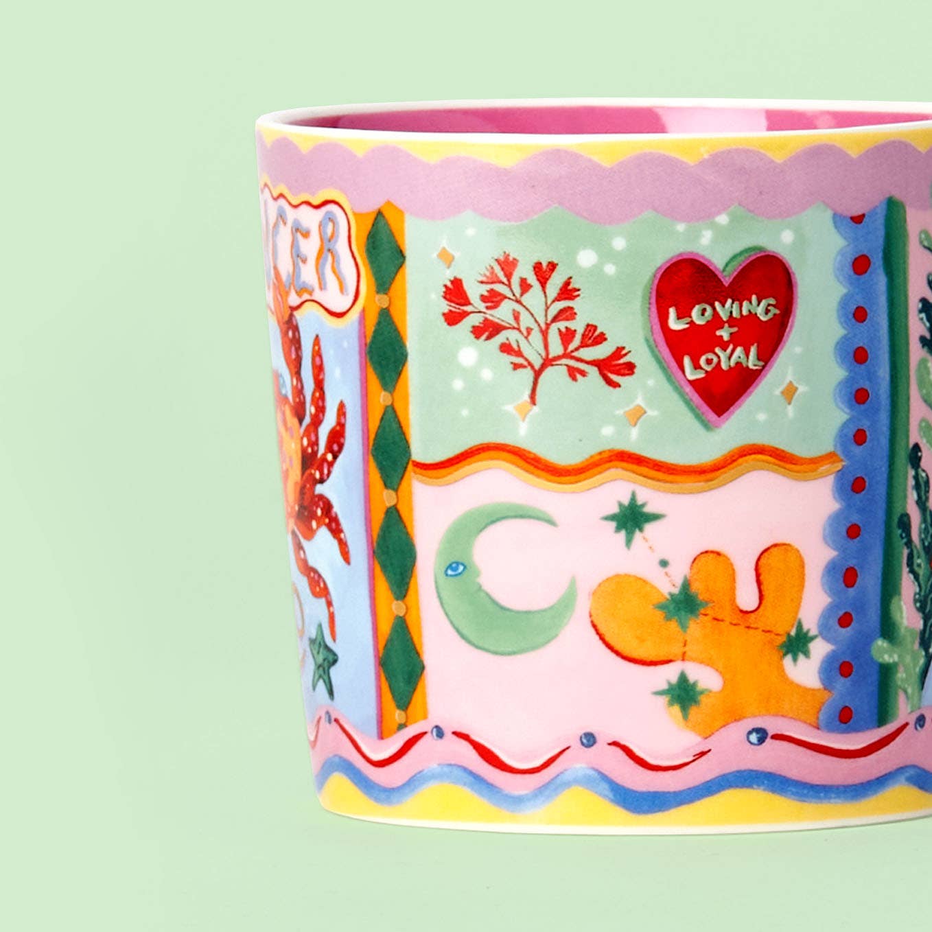 Colorful ceramic mug with decorative patterns and text on a light green background