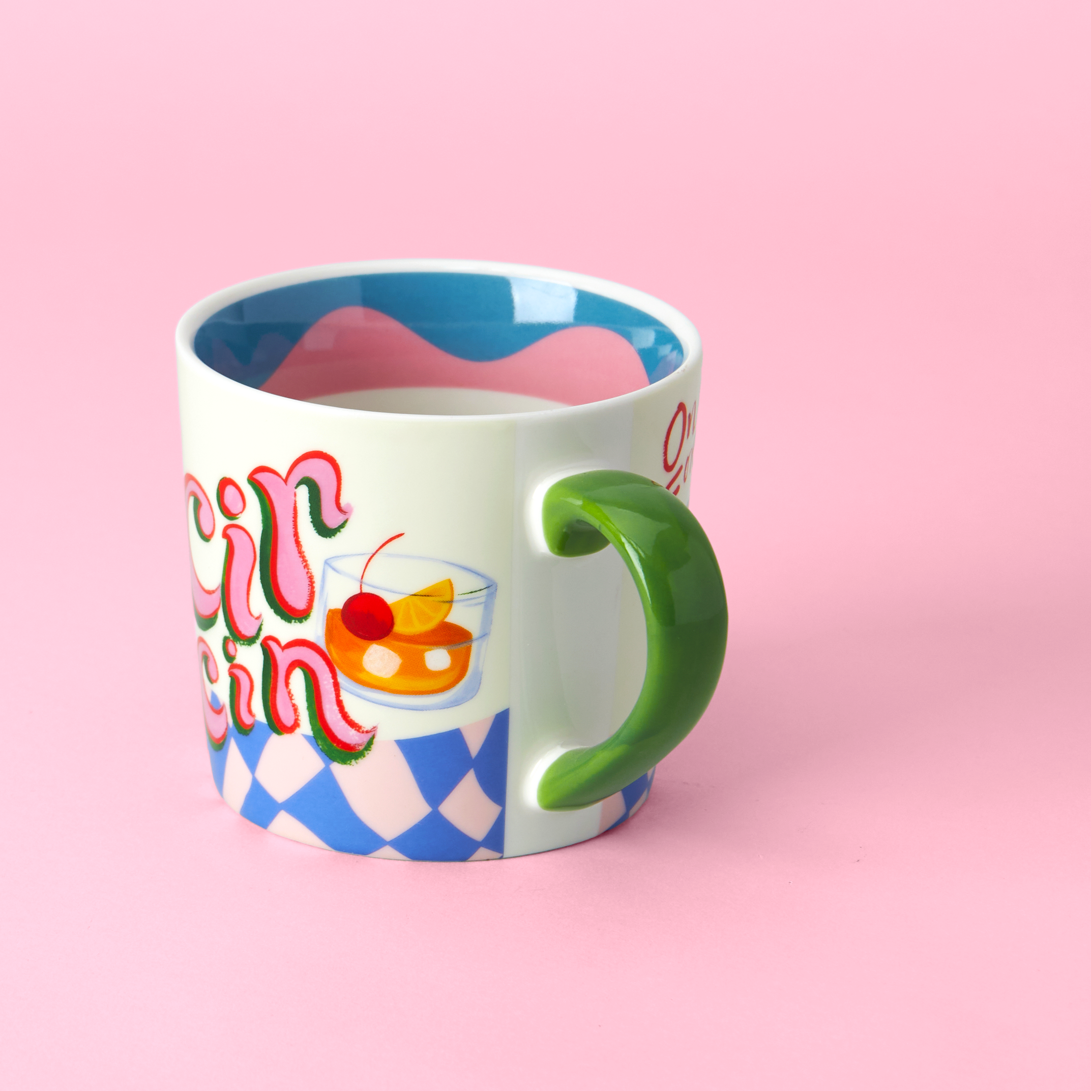 Colorful mug with a green handle on a pink background