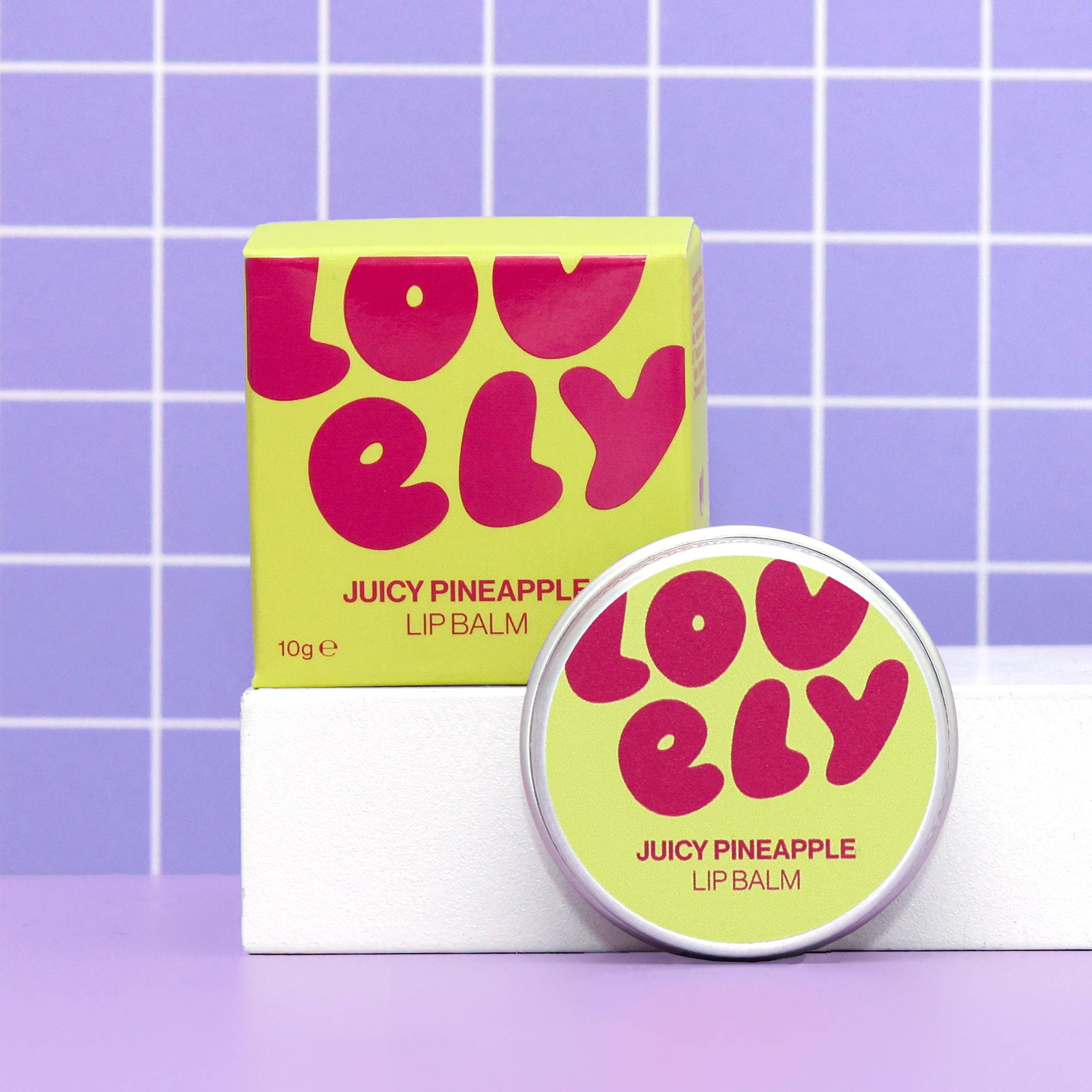 Lovelily Juicy Pineapple lip balm with packaging on a purple grid background