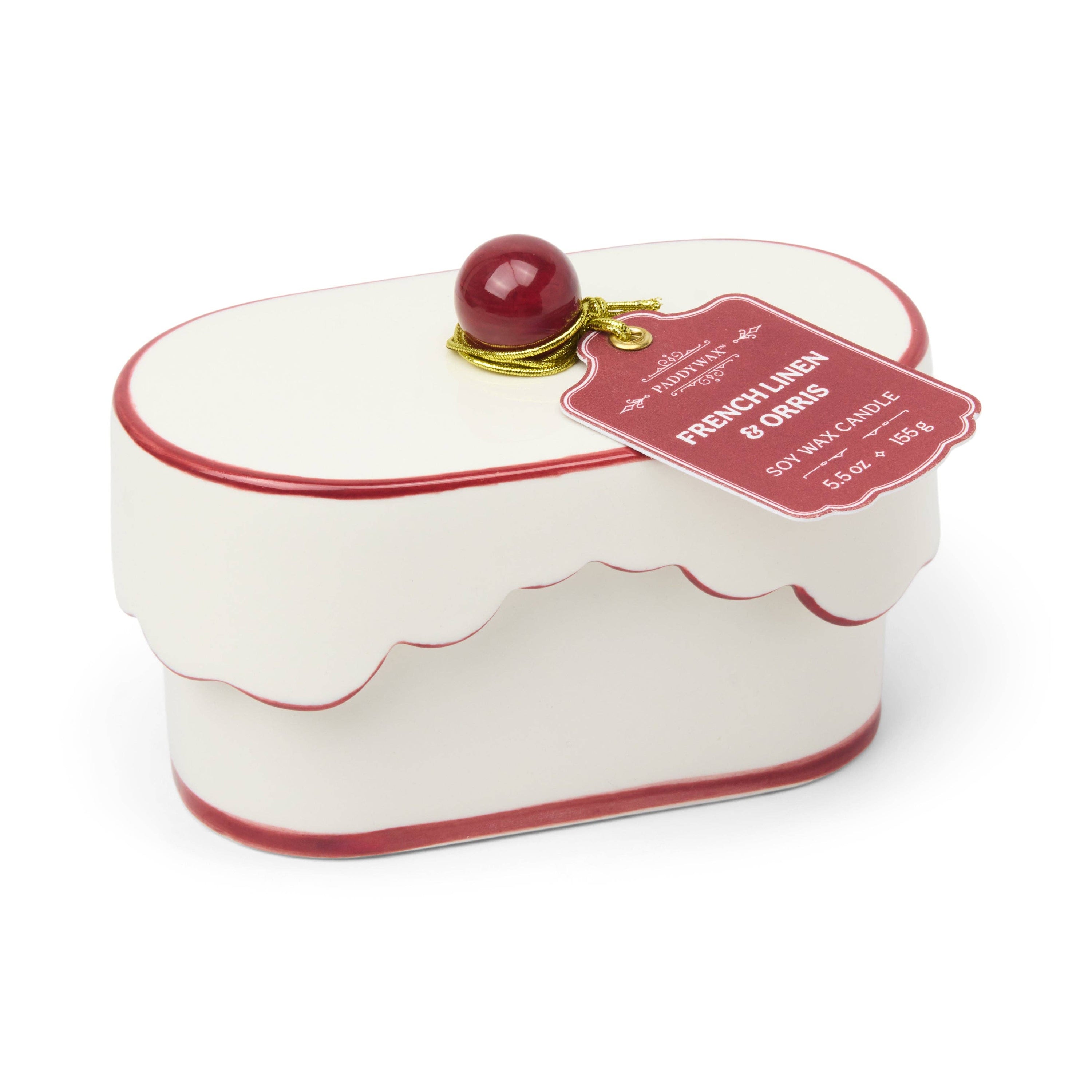 Decorative candle shaped like a cake with a cherry on top and a label on a white background
